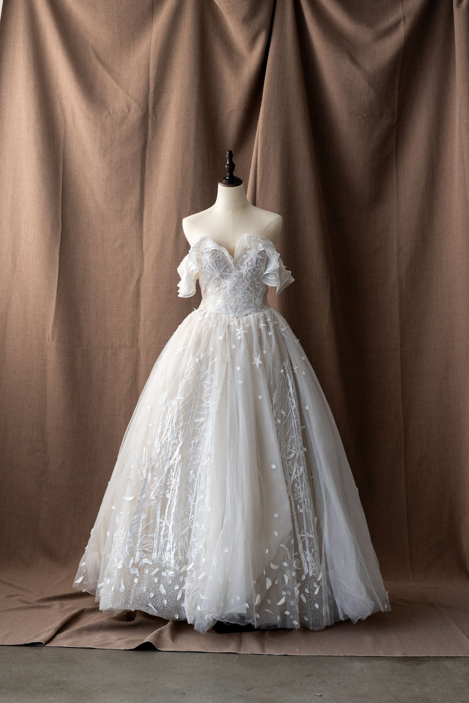 Full-length white wedding gown with star-patterned overlay and tulle skirt on display.