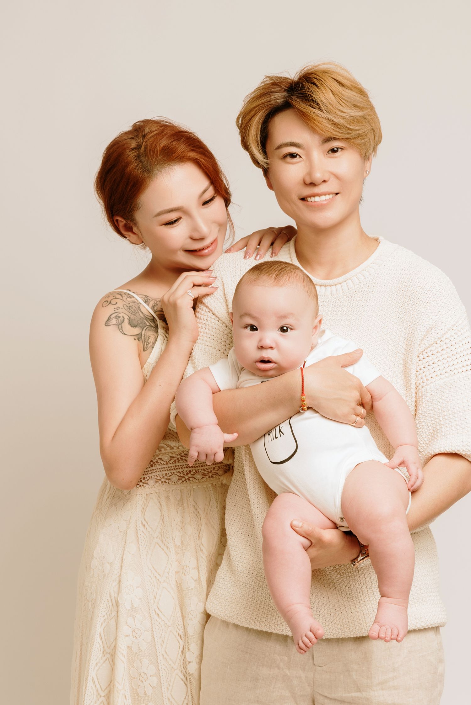 A couple in neutral tones poses with their baby in a series of sweet studio portraits.