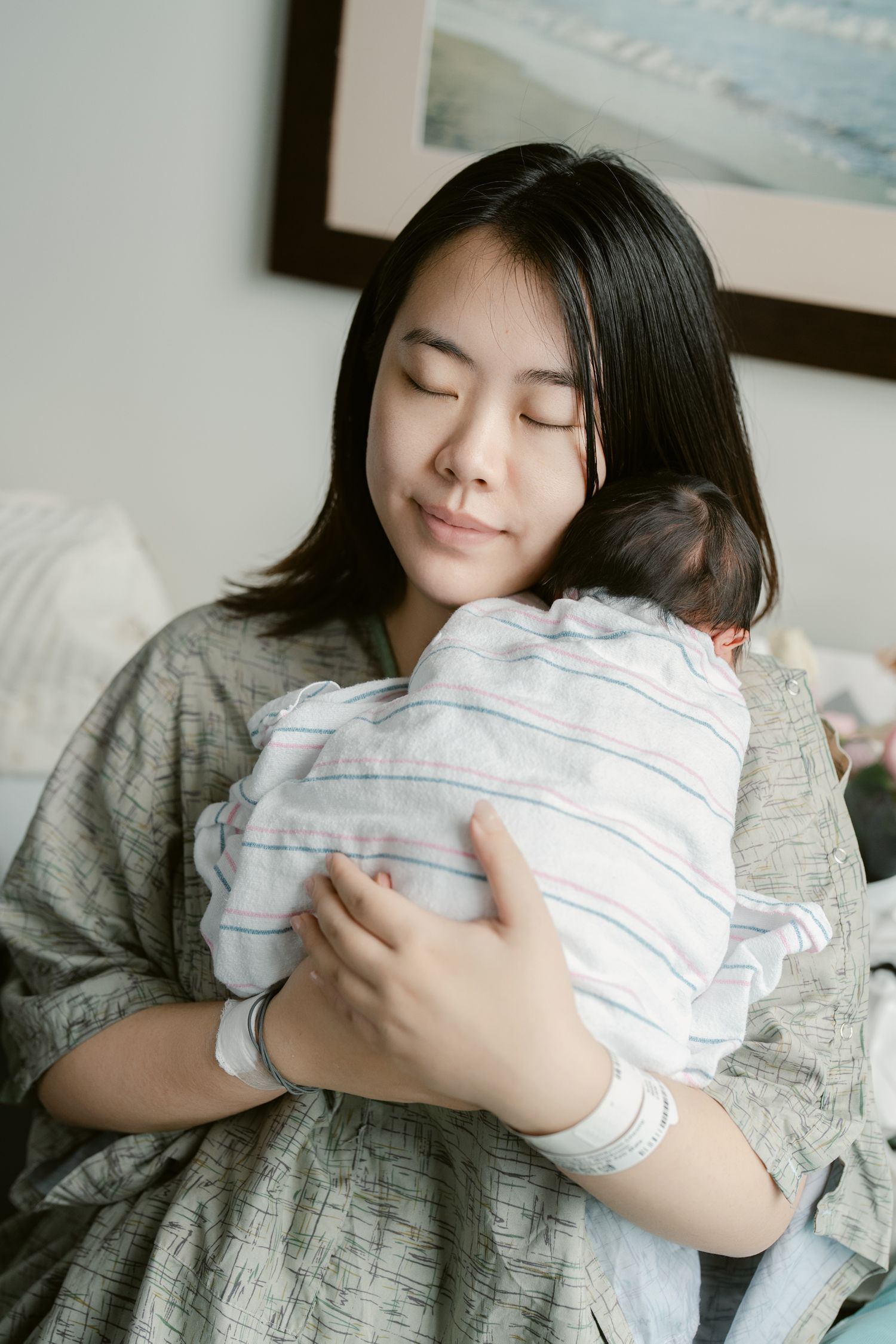 A mother holding and cuddling her swaddled newborn baby in a peaceful moment.