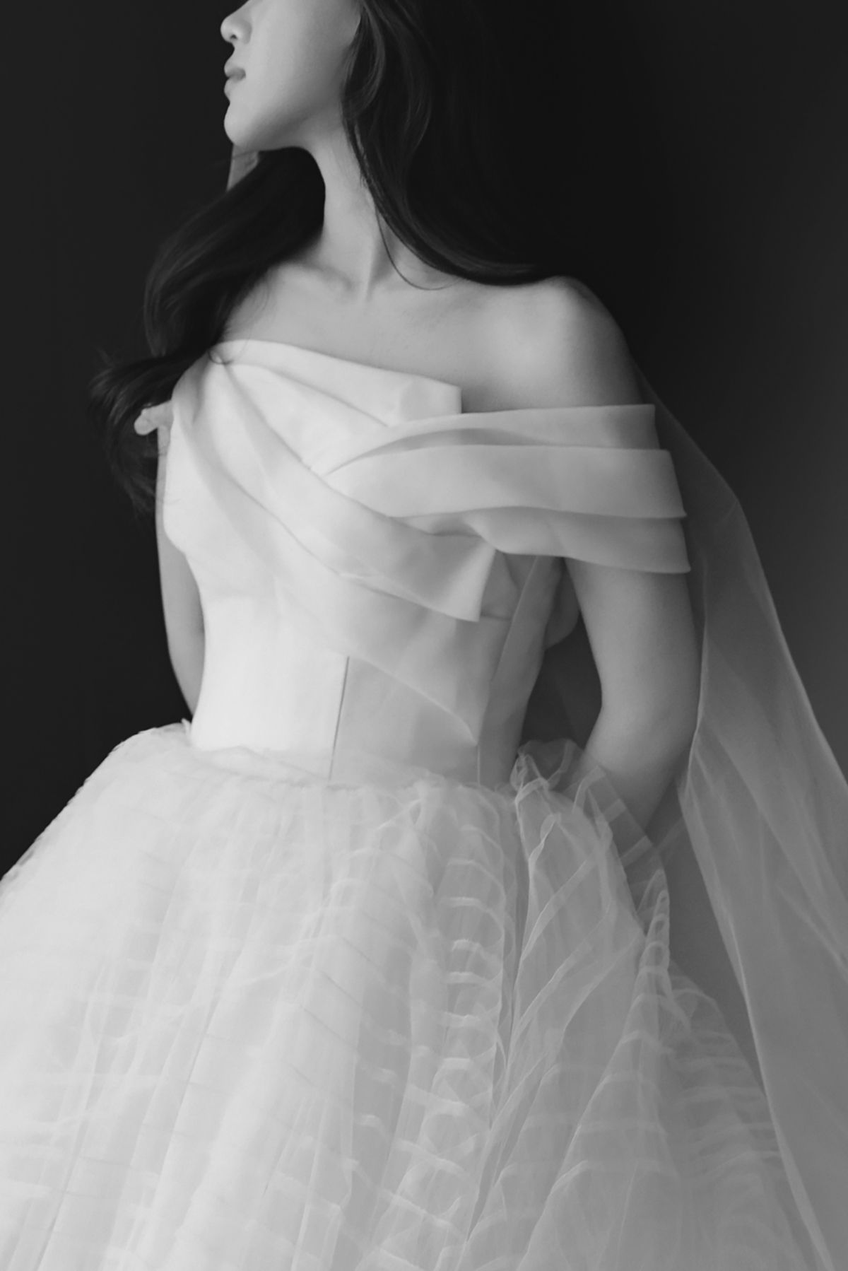 Off-shoulder bridal gown with structured bodice and ethereal tulle skirt captured in artistic black and white.