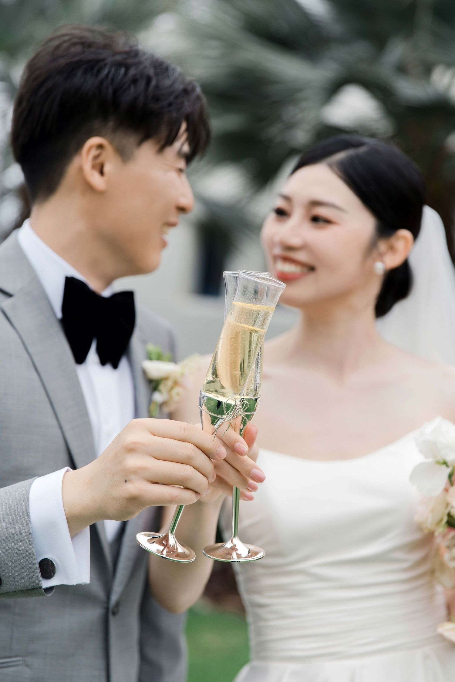 Newlyweds toast with champagne glasses in an outdoor celebration.