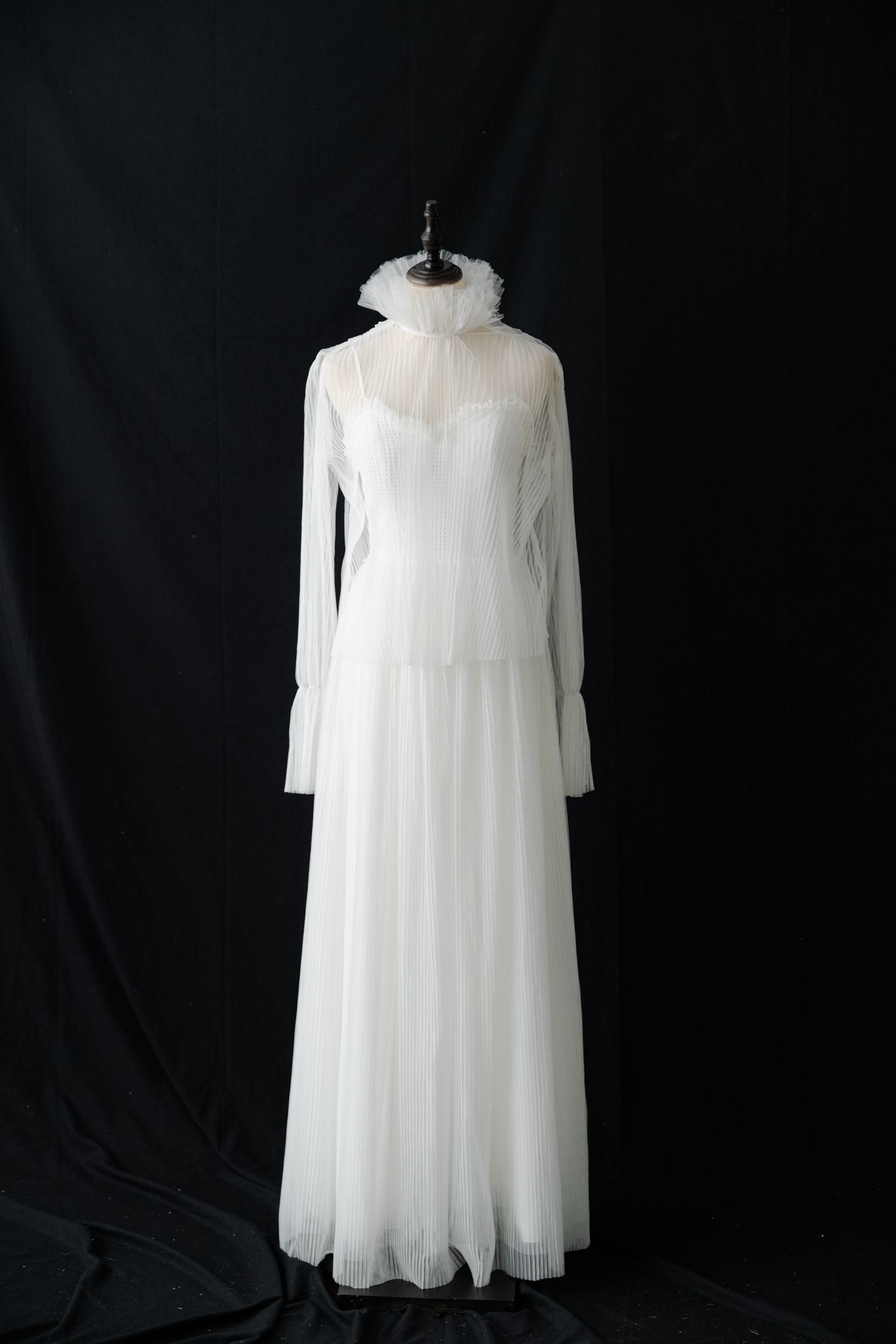 Ethereal white chiffon dress with long sleeves displayed against black background.