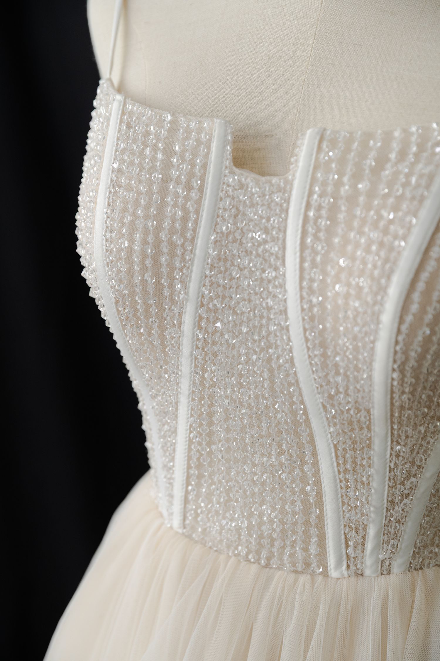Close-up detail of beaded bodice on white wedding gown with pearl embellishments.