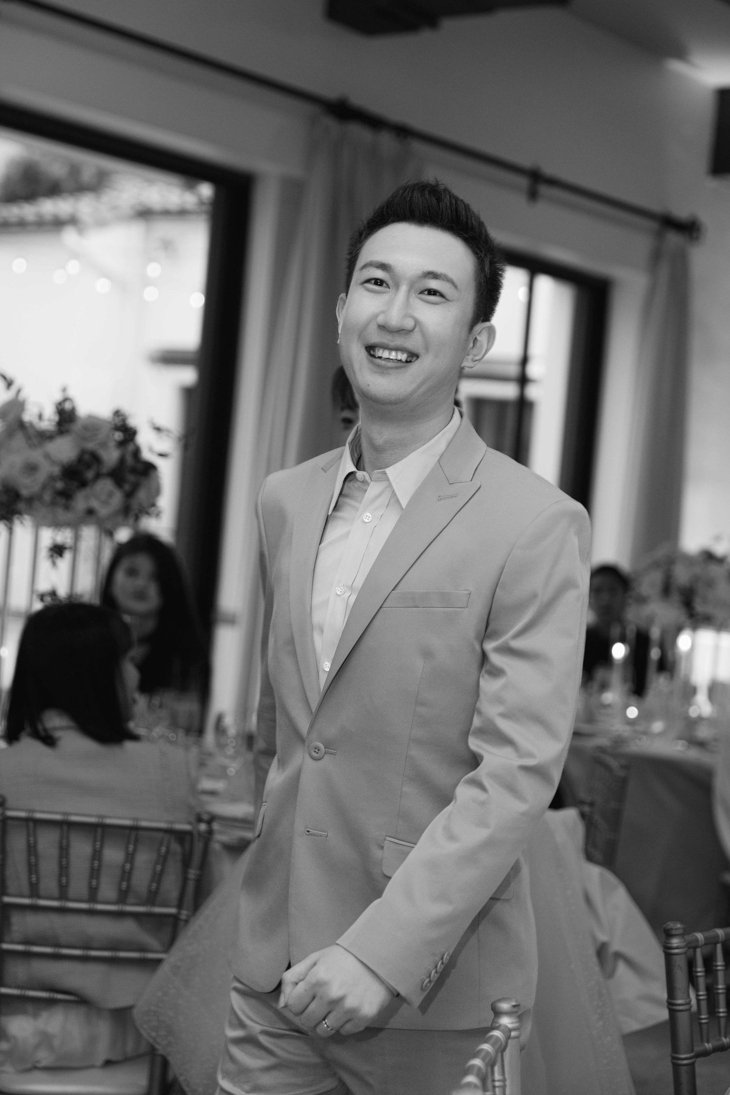 Black and white portrait of a person in a light colored suit at a formal event.