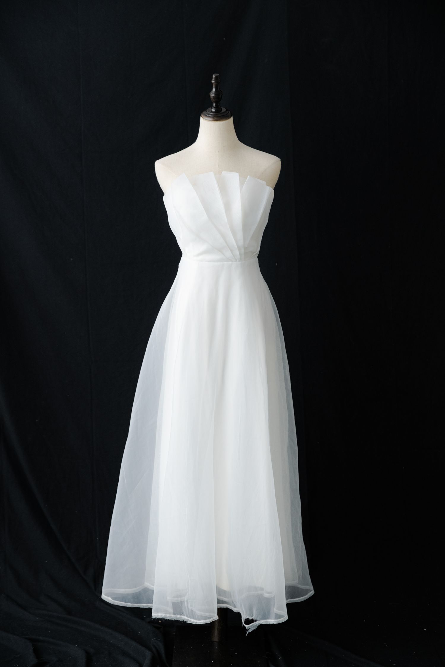 Simple white strapless dress with flowing tulle skirt on display.