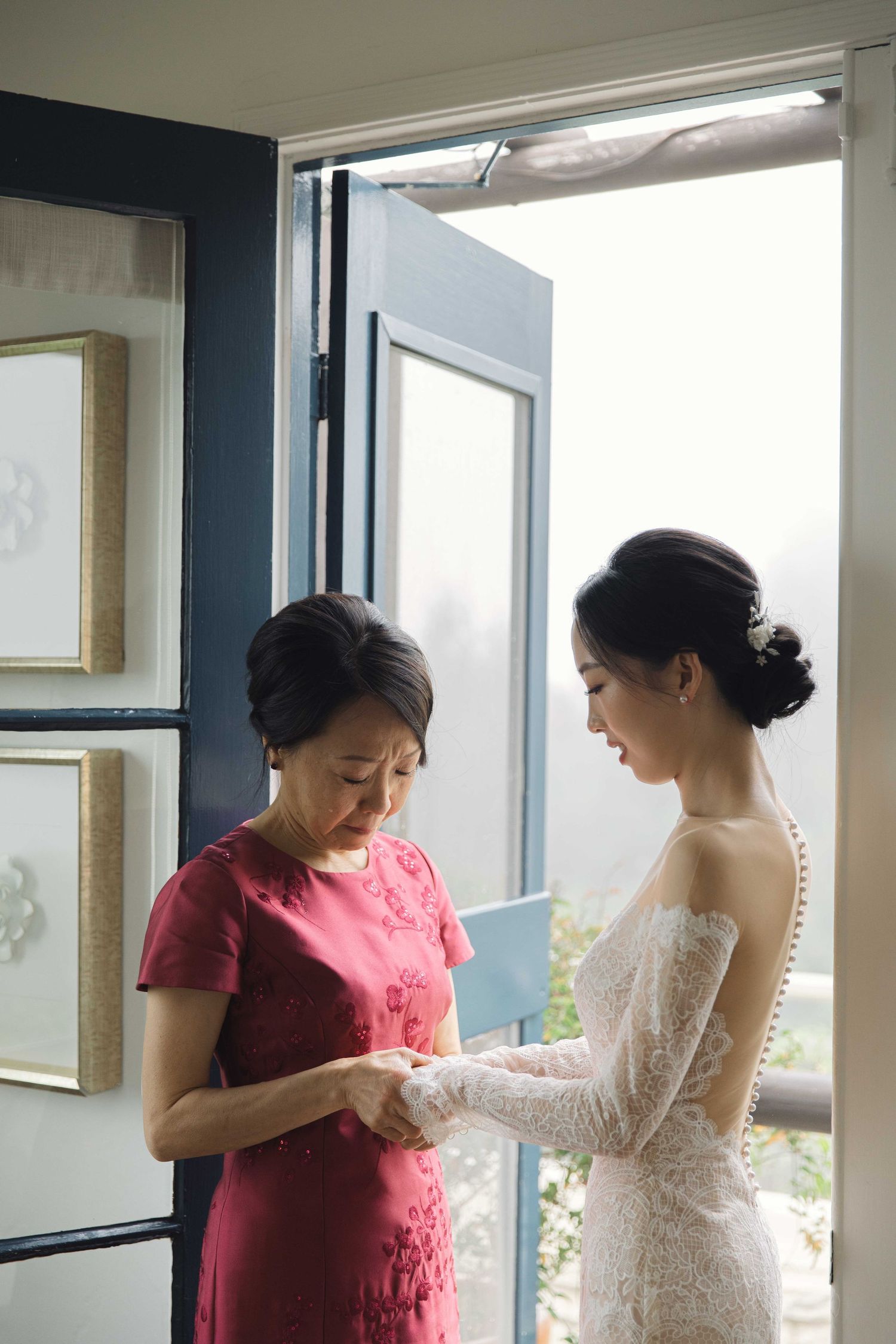 A wedding preparation scene showing final dress adjustments in a sunlit room.