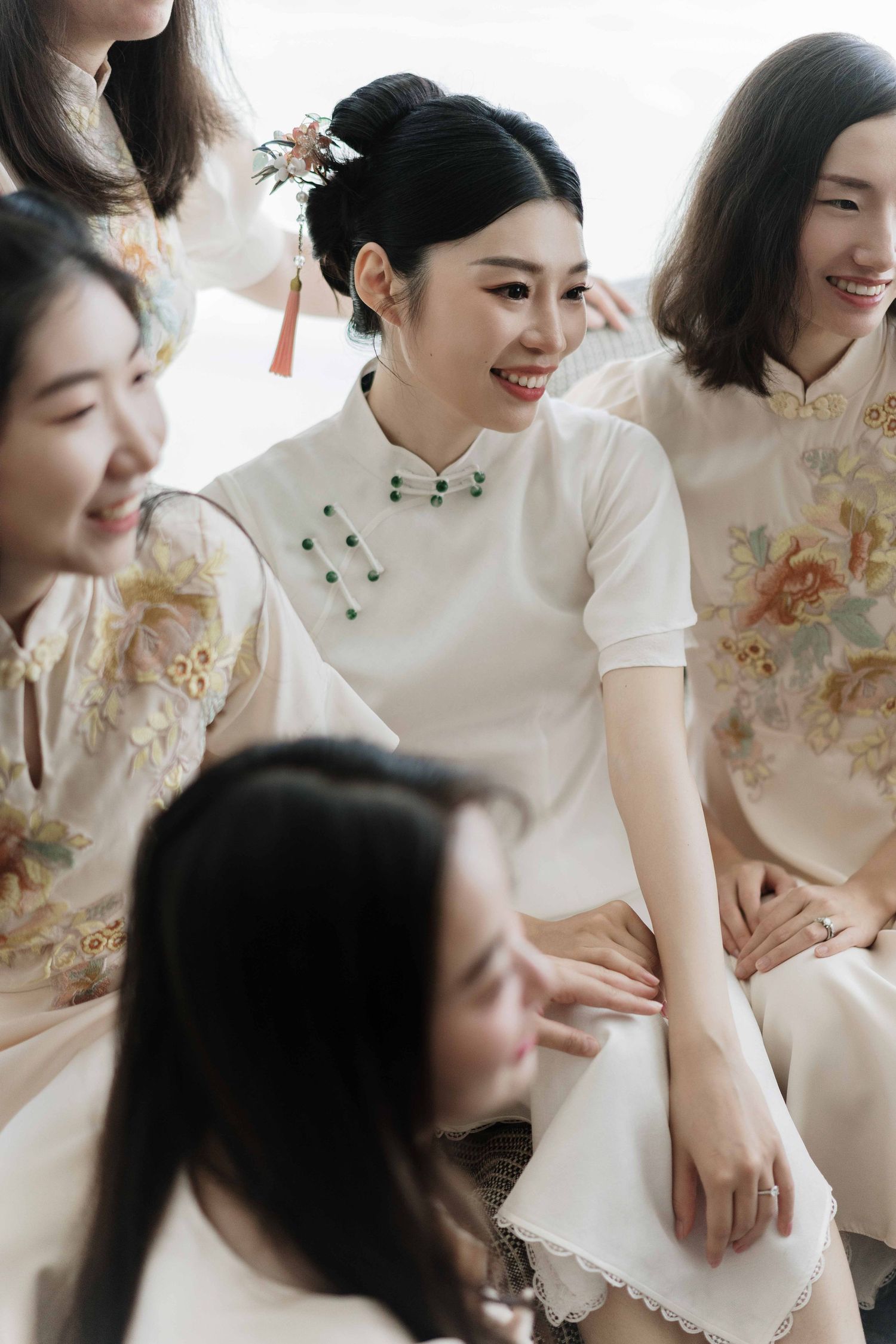 Group wearing traditional white and floral qipao dresses sitting together.