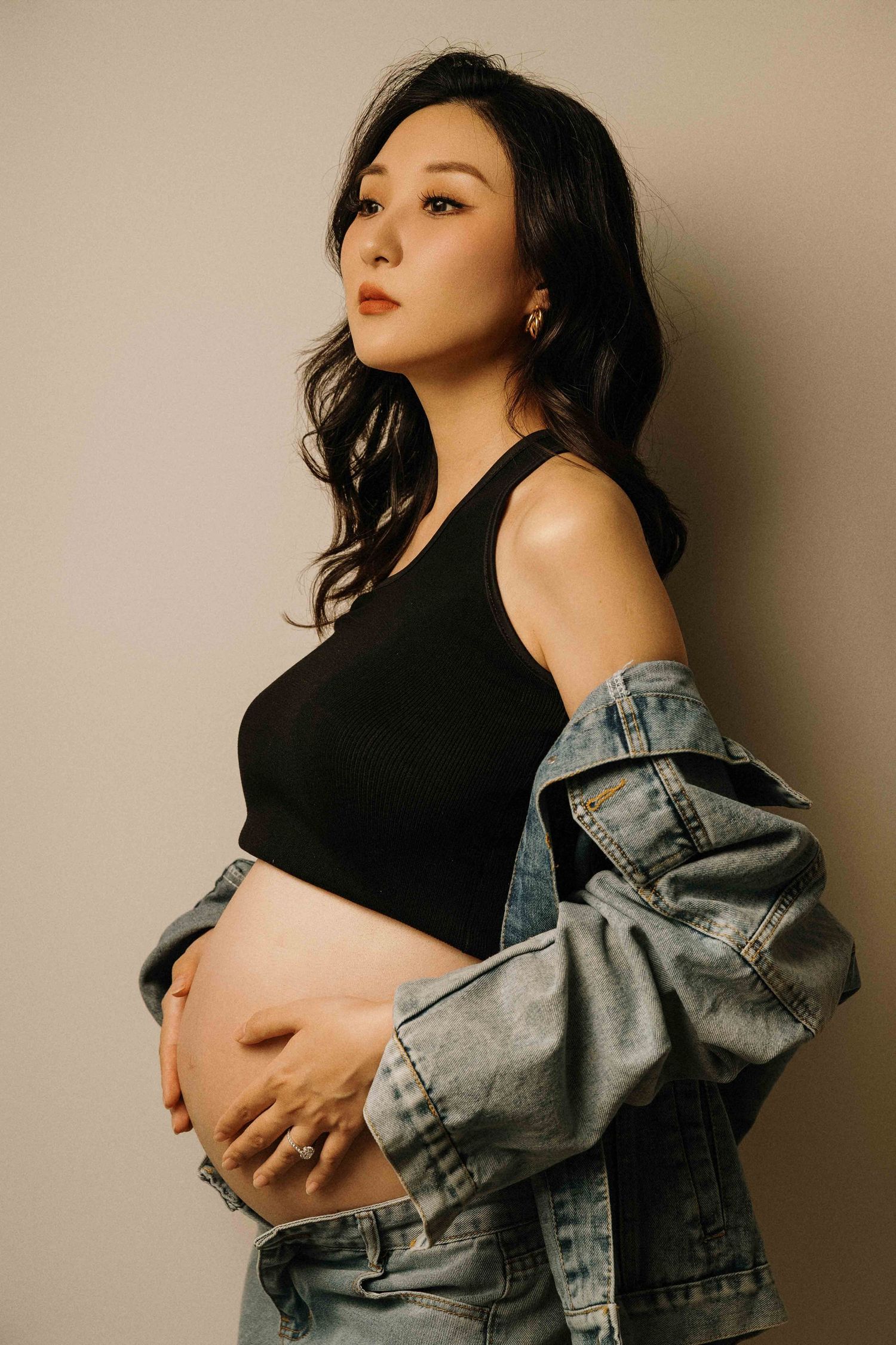 Maternity photos featuring denim jacket and black top in warm lighting.