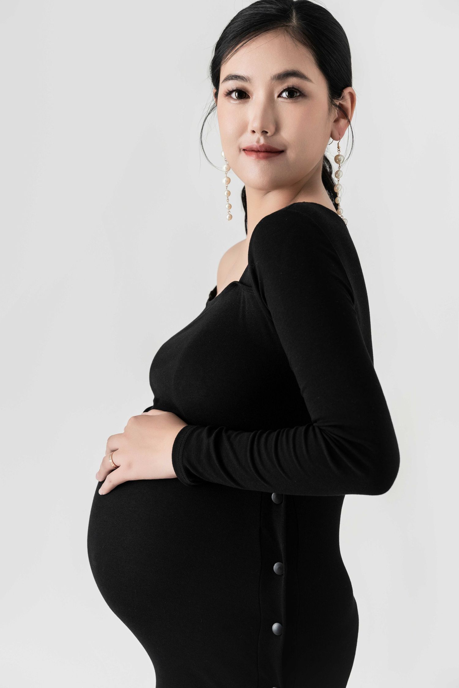 Studio portraits in fitted black long-sleeve dress against white background.