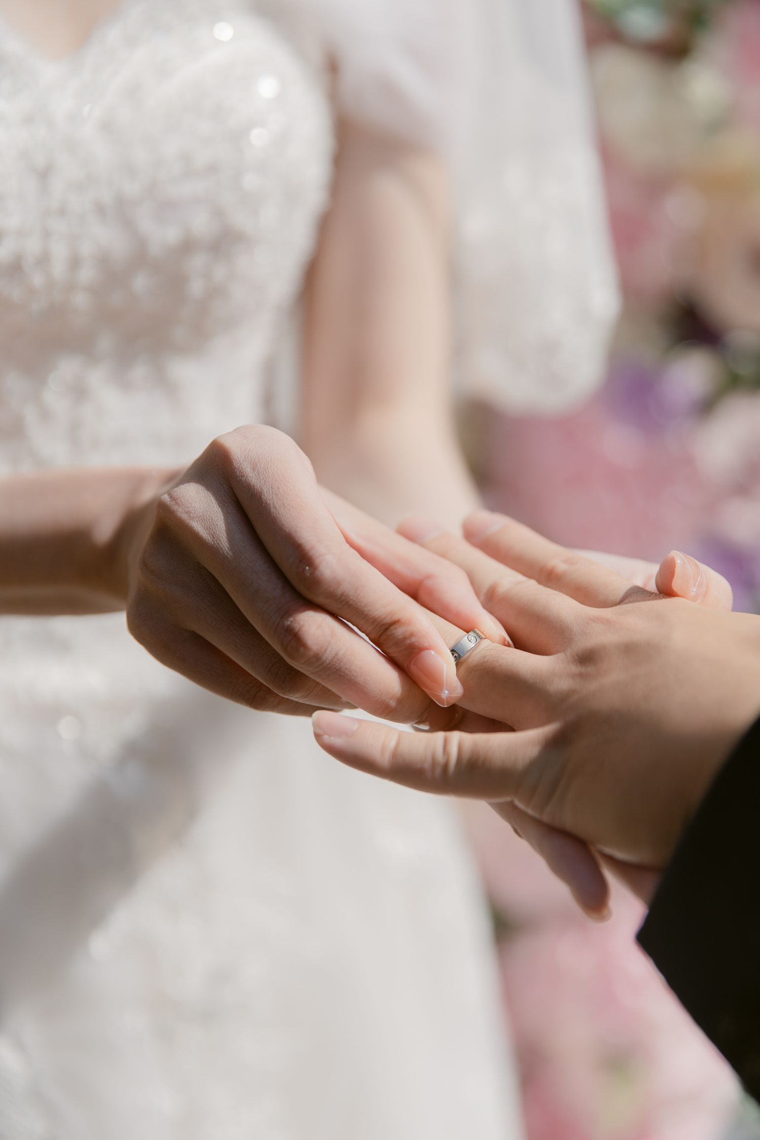 Close-up of hands exchanging wedding rings during ceremony.