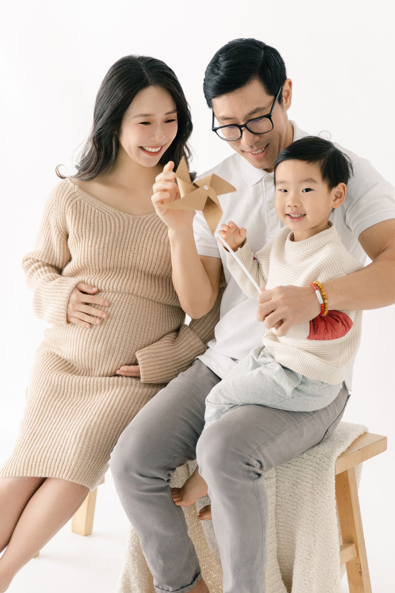 Candid family maternity photos showing joyful interactions on wooden bench.