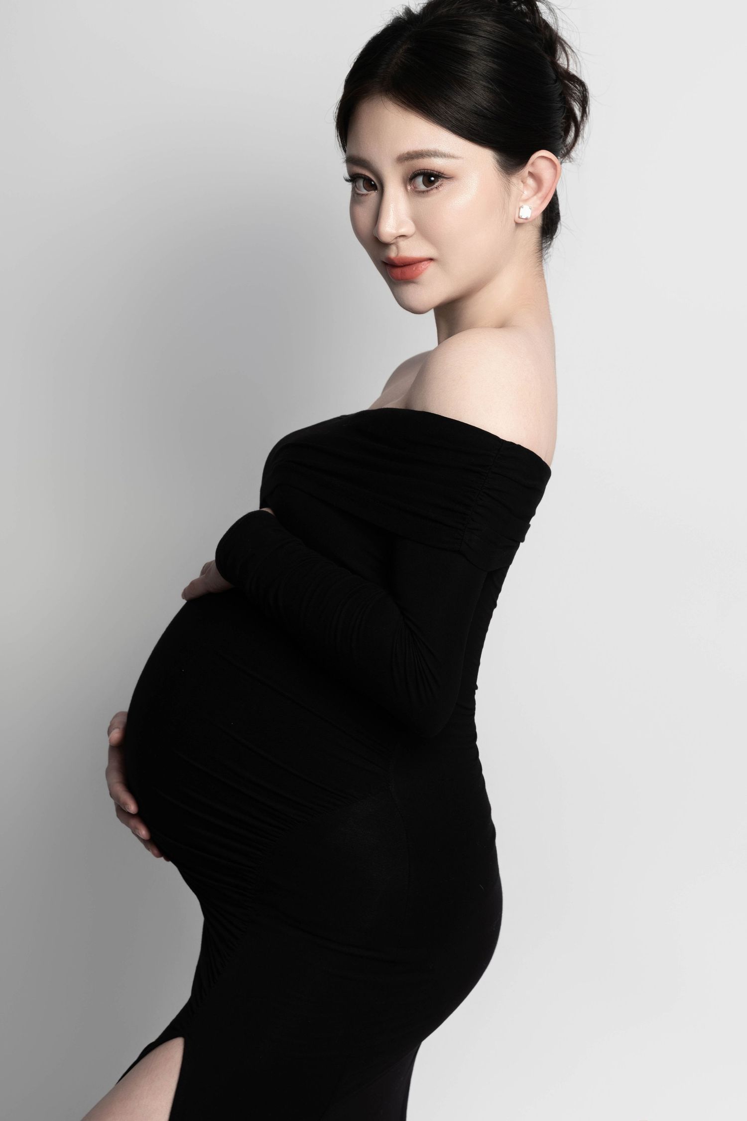 Elegant off-shoulder maternity portrait against white background showcasing pregnancy.