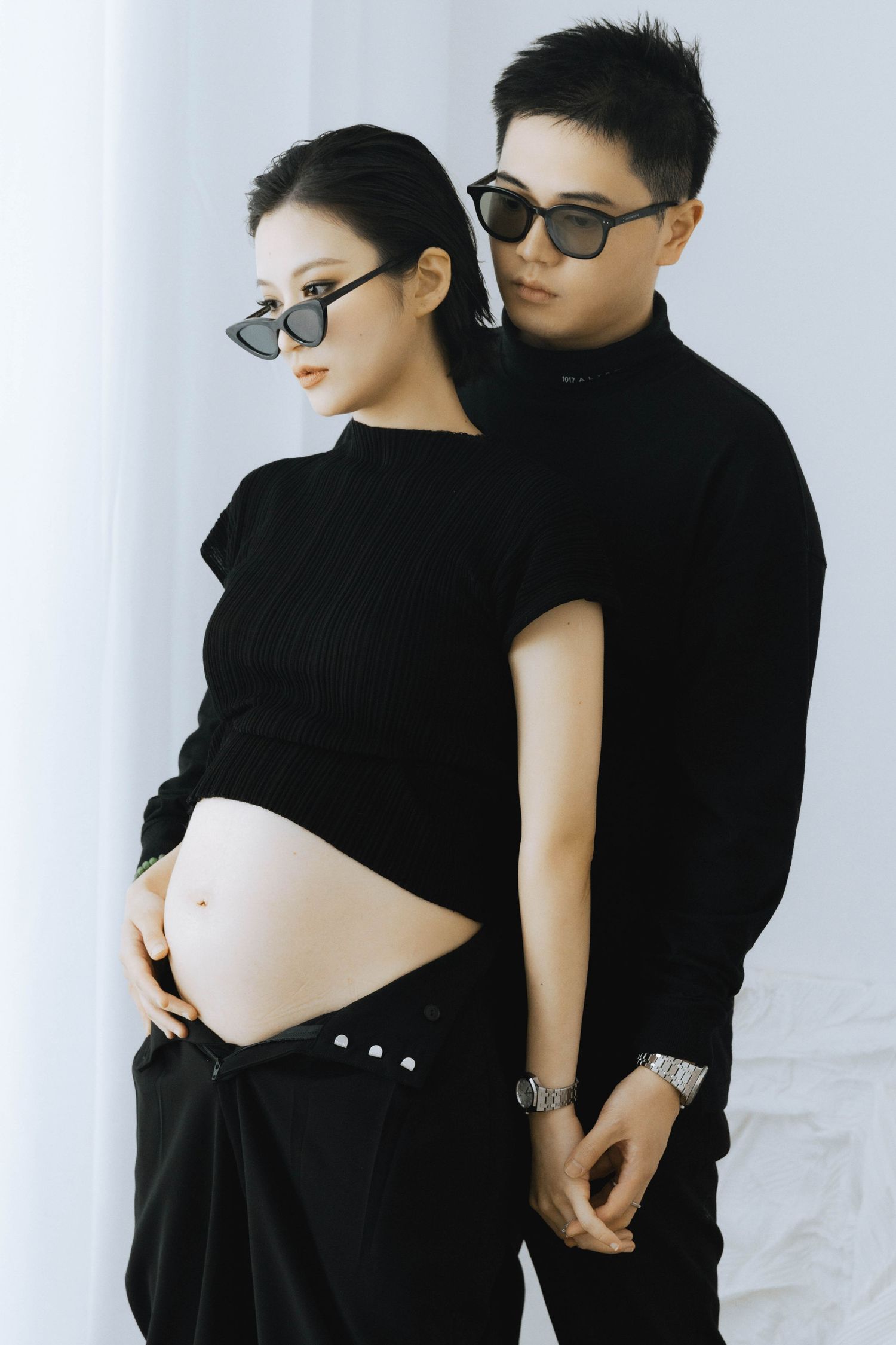 Modern maternity couple photos in matching black outfits against white background.