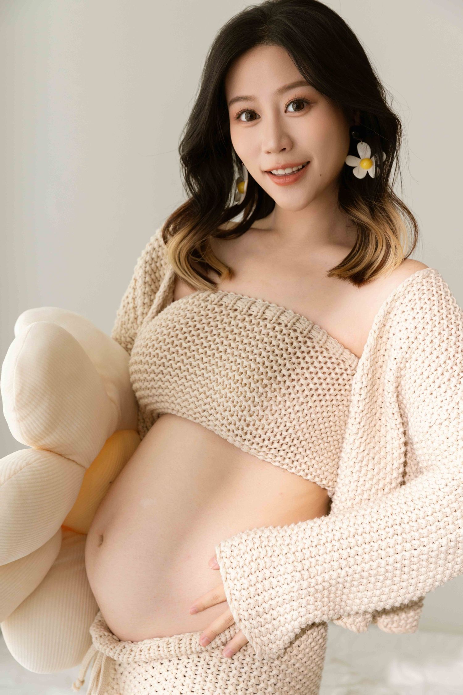 Artistic maternity photos in cream knit sweater against neutral background.