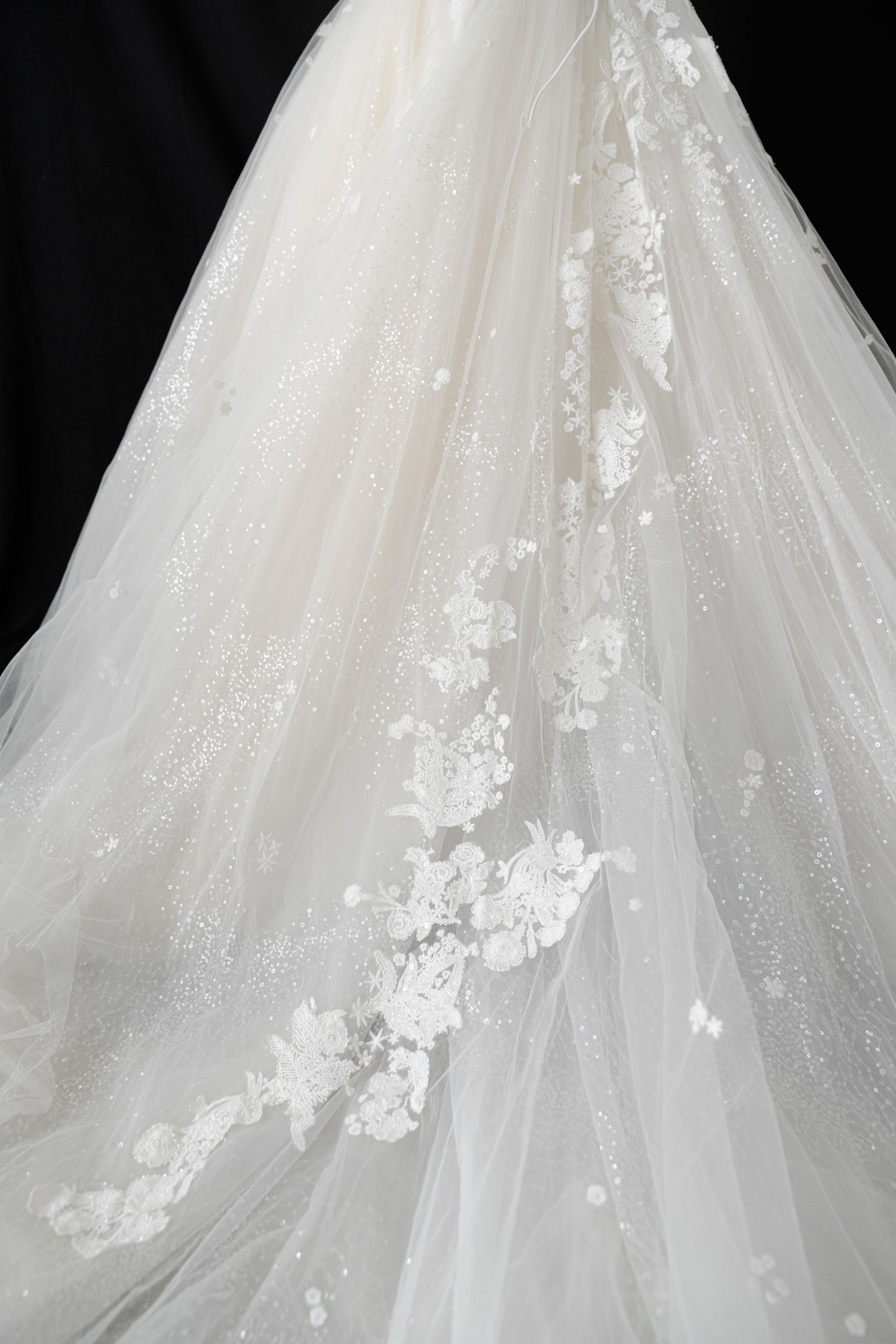 Sparkling tulle skirt with scattered lace appliques on white wedding gown.
