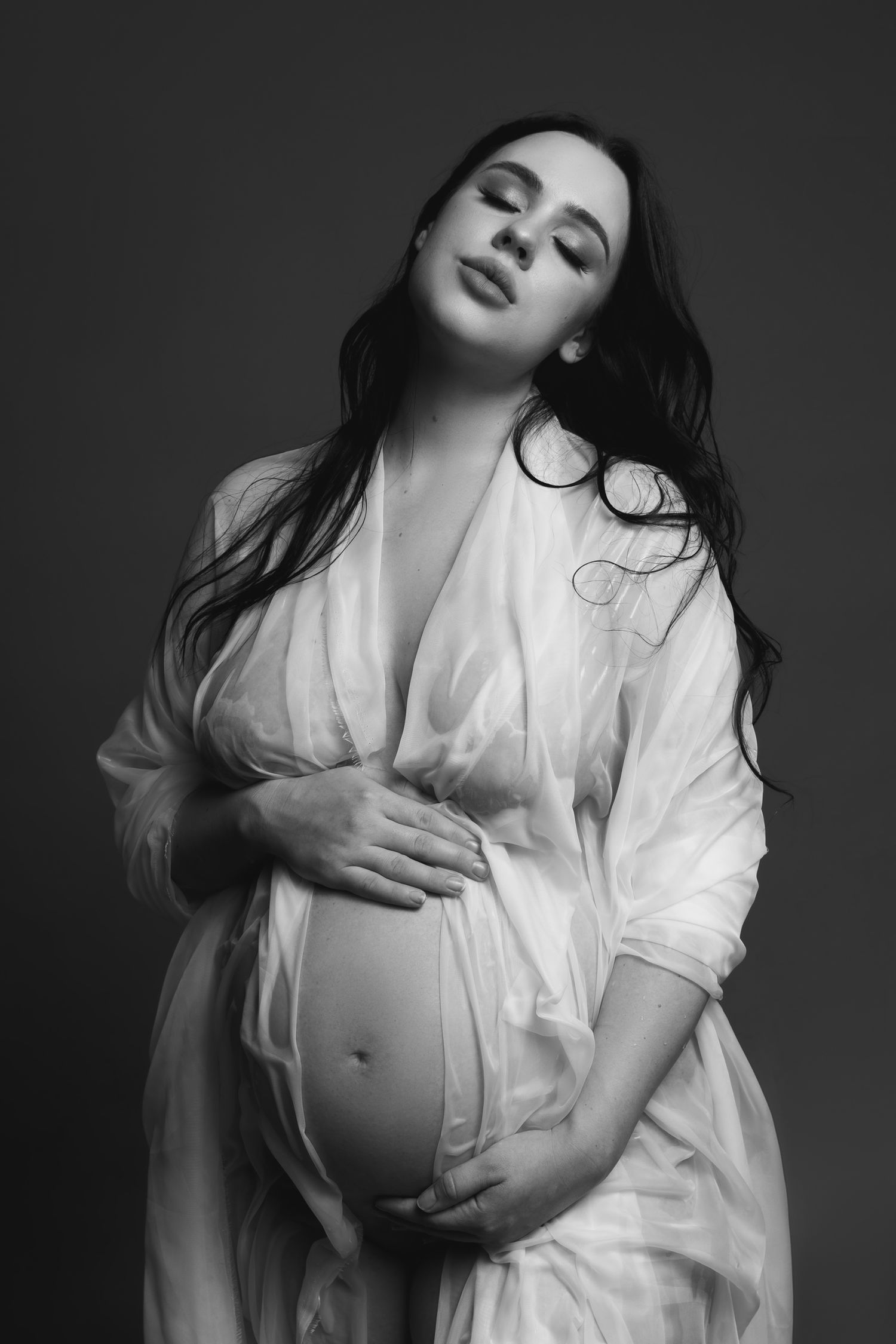 Artistic black and white maternity portraits with flowing white shirt and dramatic lighting.