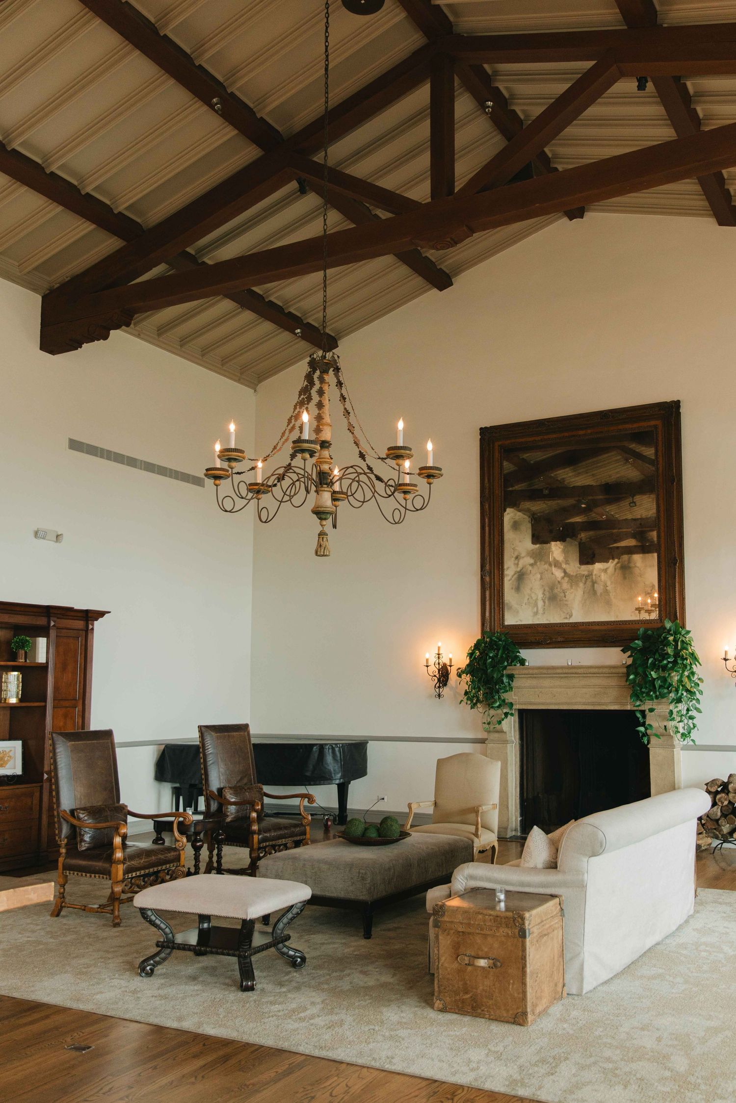 Rustic reception room with exposed beam ceiling, chandelier, and elegant furnishings.