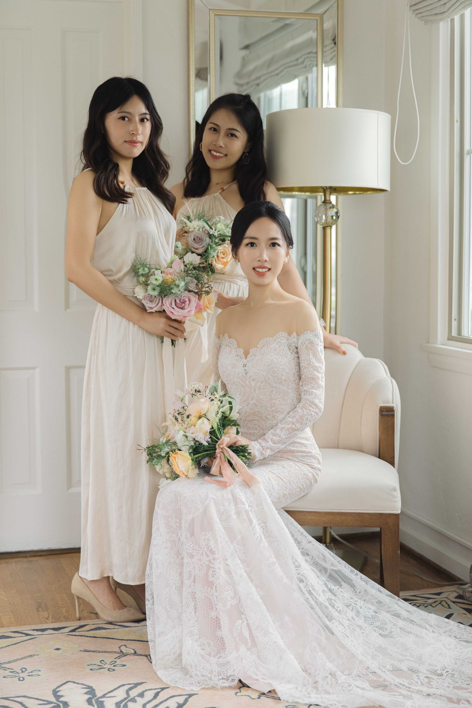Wedding preparations in bright room with bride and attendants in white dresses.