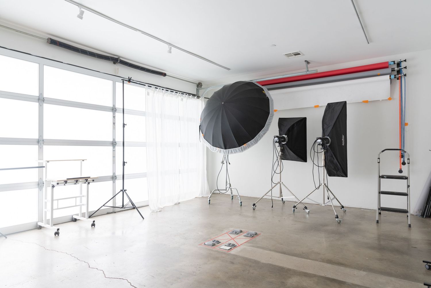 Spacious white photography studio with natural light windows and professional lighting setup.