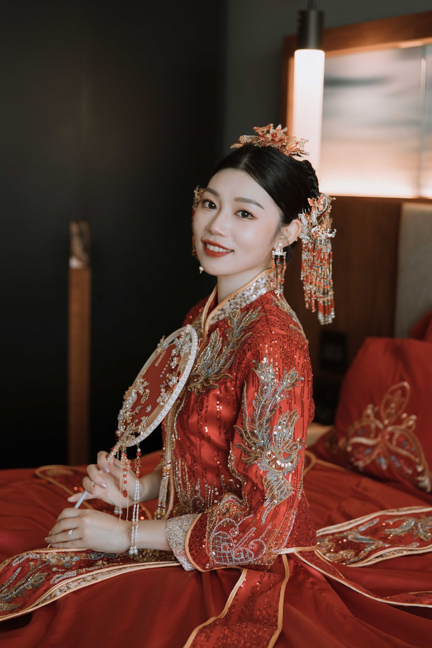 Traditional Chinese bride wearing ornate red qipao dress and golden hair accessories.