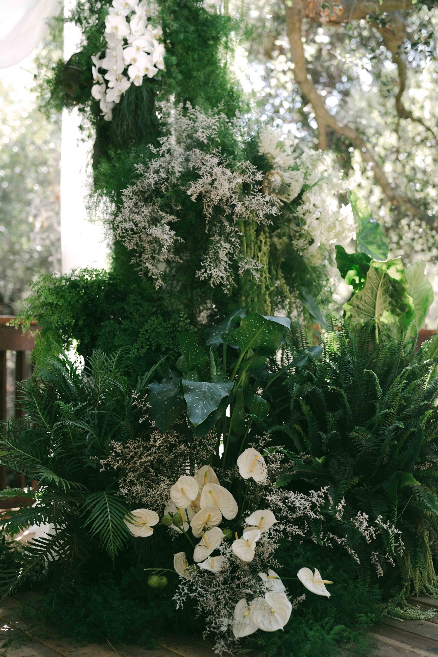 Lush floral arrangement with white orchids and greenery in an outdoor garden setting.