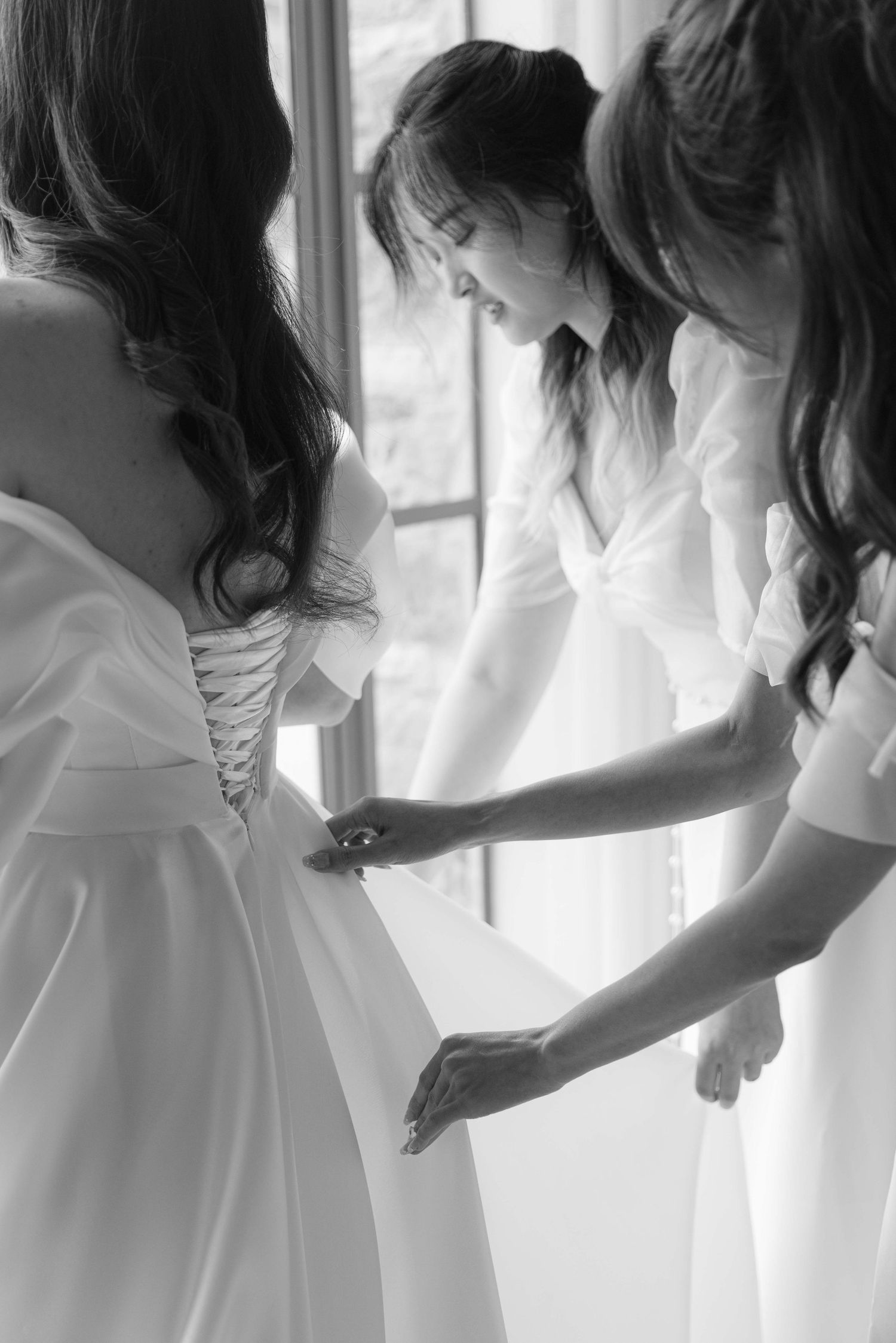 Series of black and white photos showing the back details of a white wedding dress being adjusted.