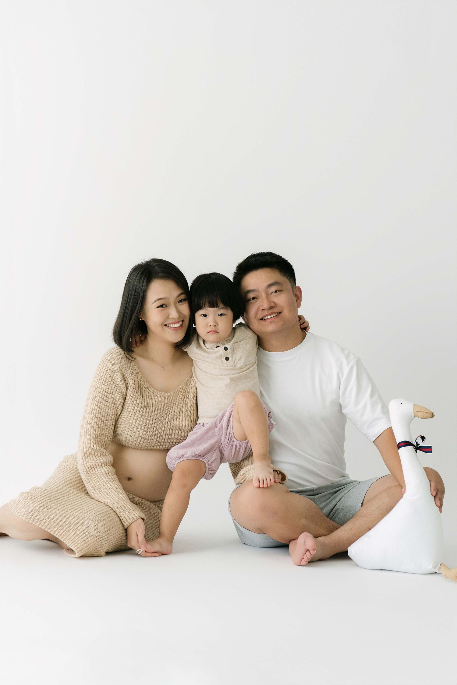 Intimate family maternity portraits with casual poses on white background.