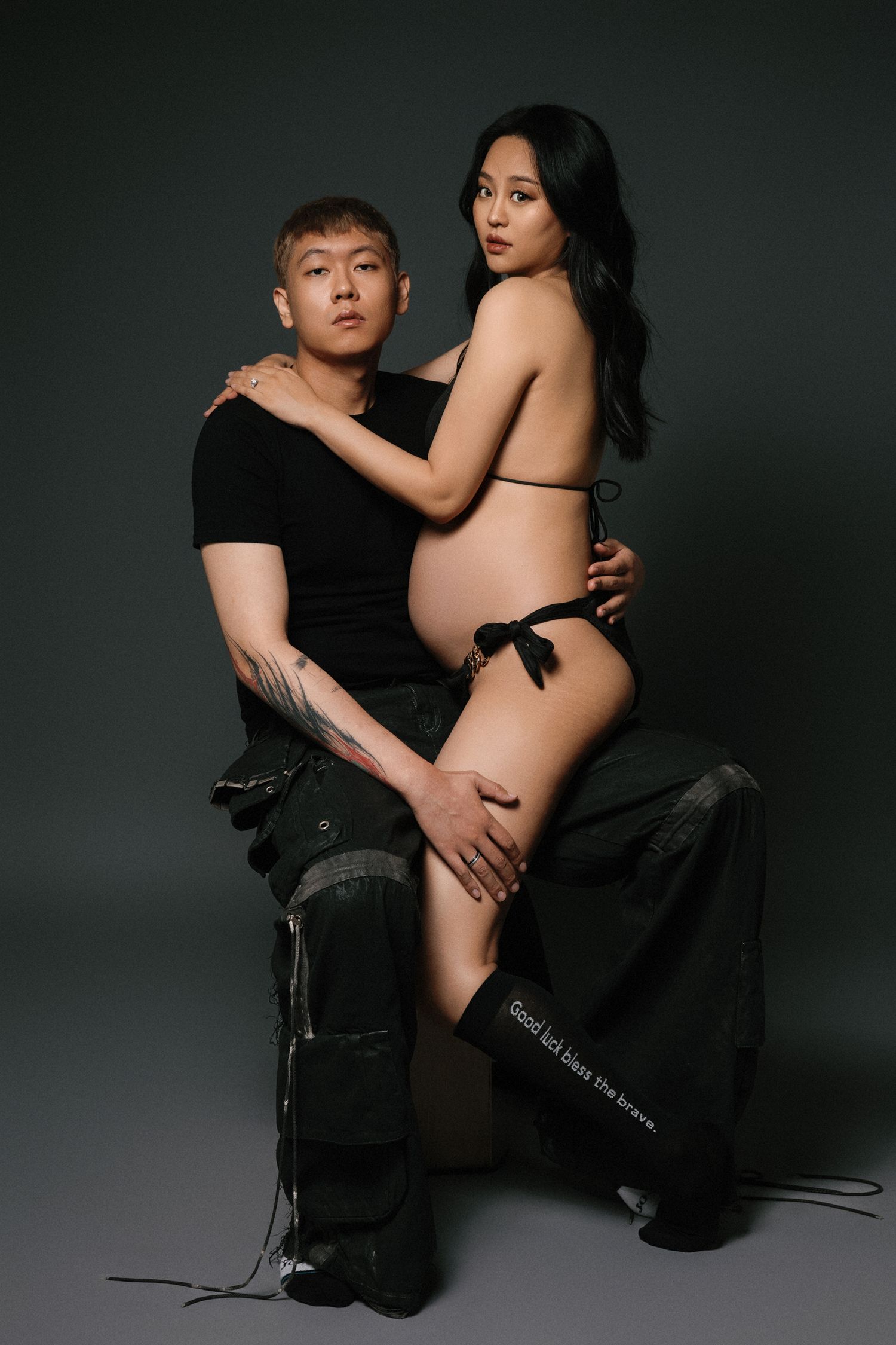 Intimate artistic studio portrait series of couple in black against dark grey background.
