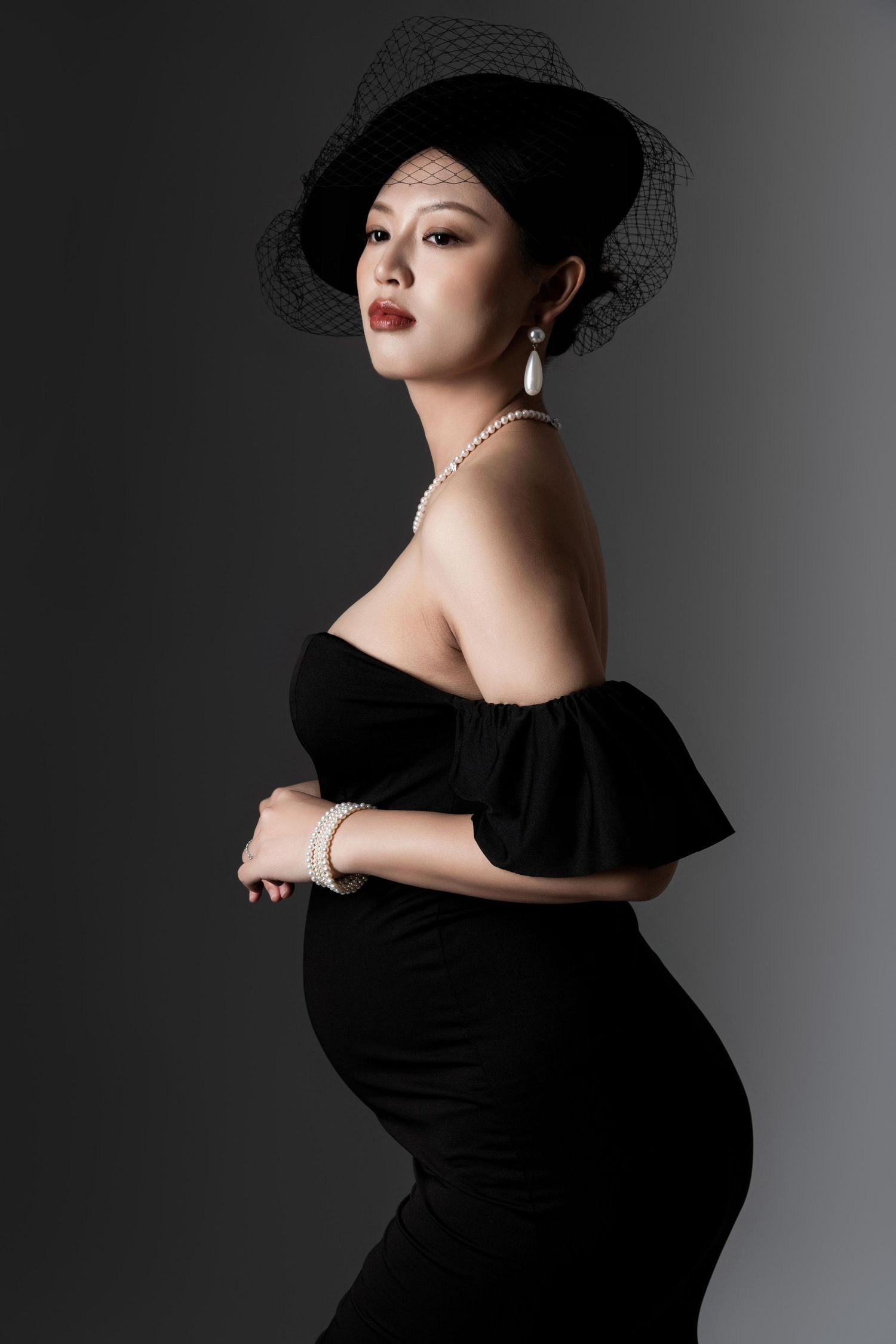 Artistic black and white portrait series featuring dramatic poses in a black dress against dark backdrop.