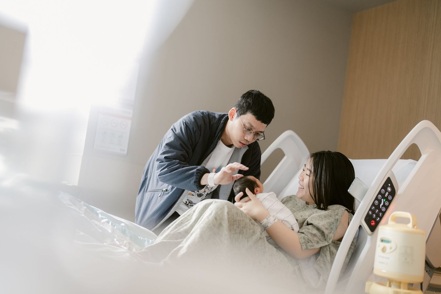 Parents sharing intimate moment with their newborn in hospital room.