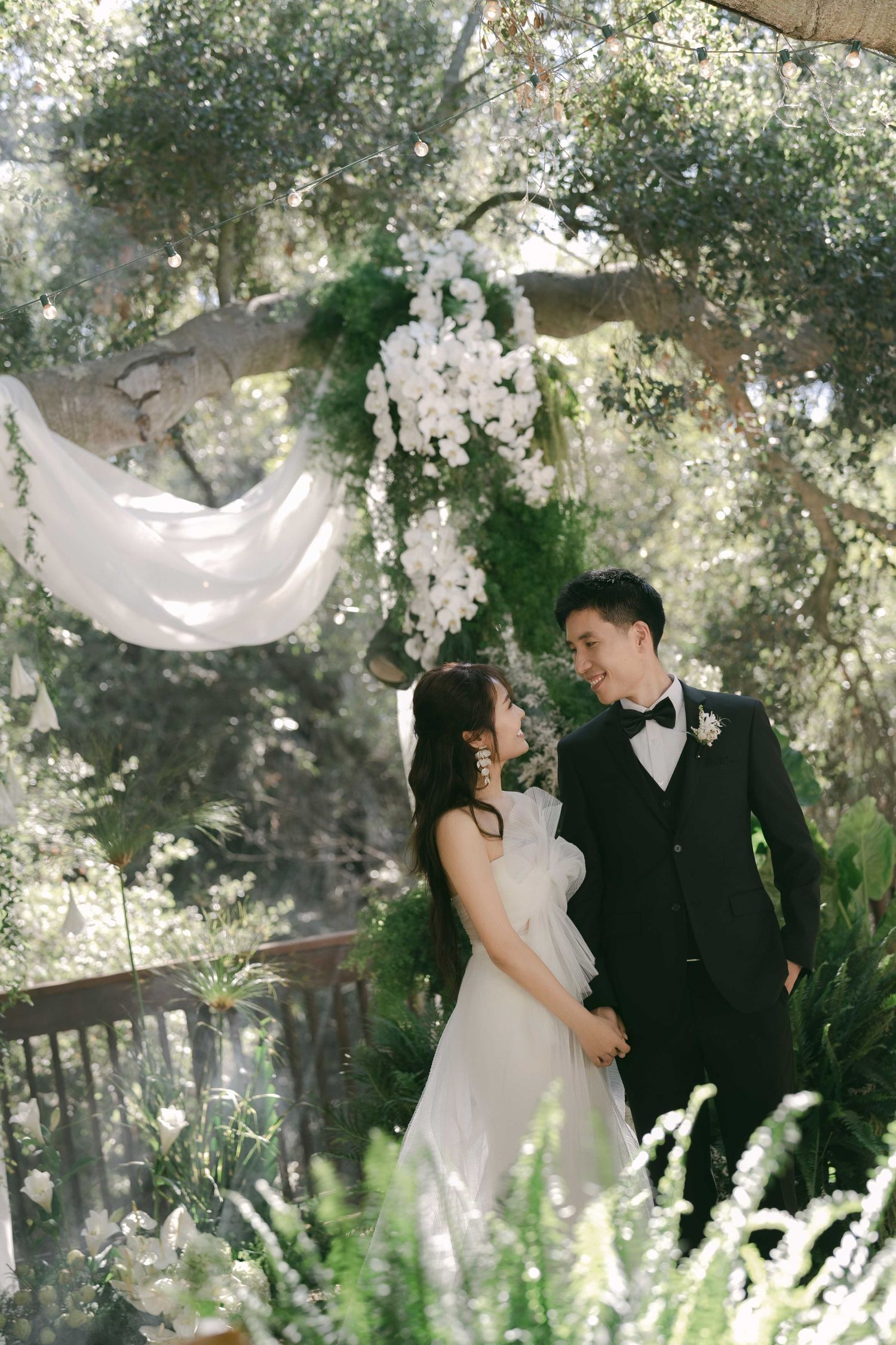 Romantic garden wedding setup with white orchids and flowing fabric decorations.