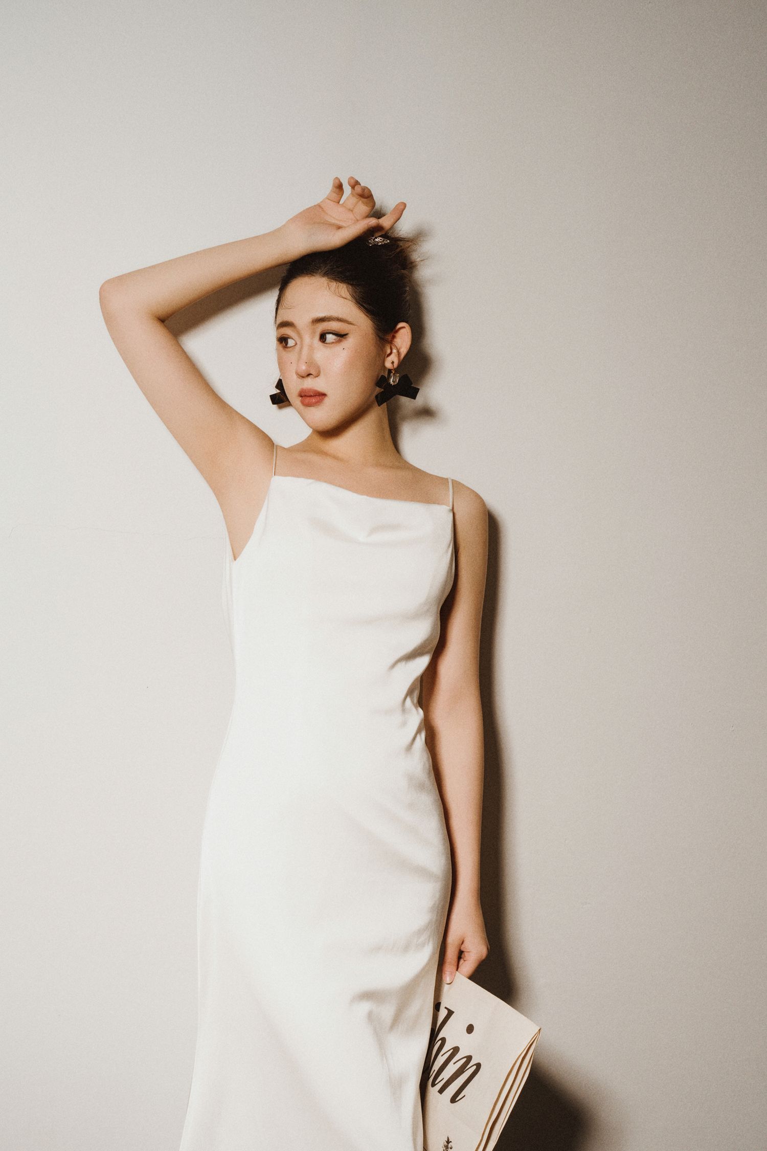 Fashion editorial shot showing elegant white dress against minimalist backdrop.