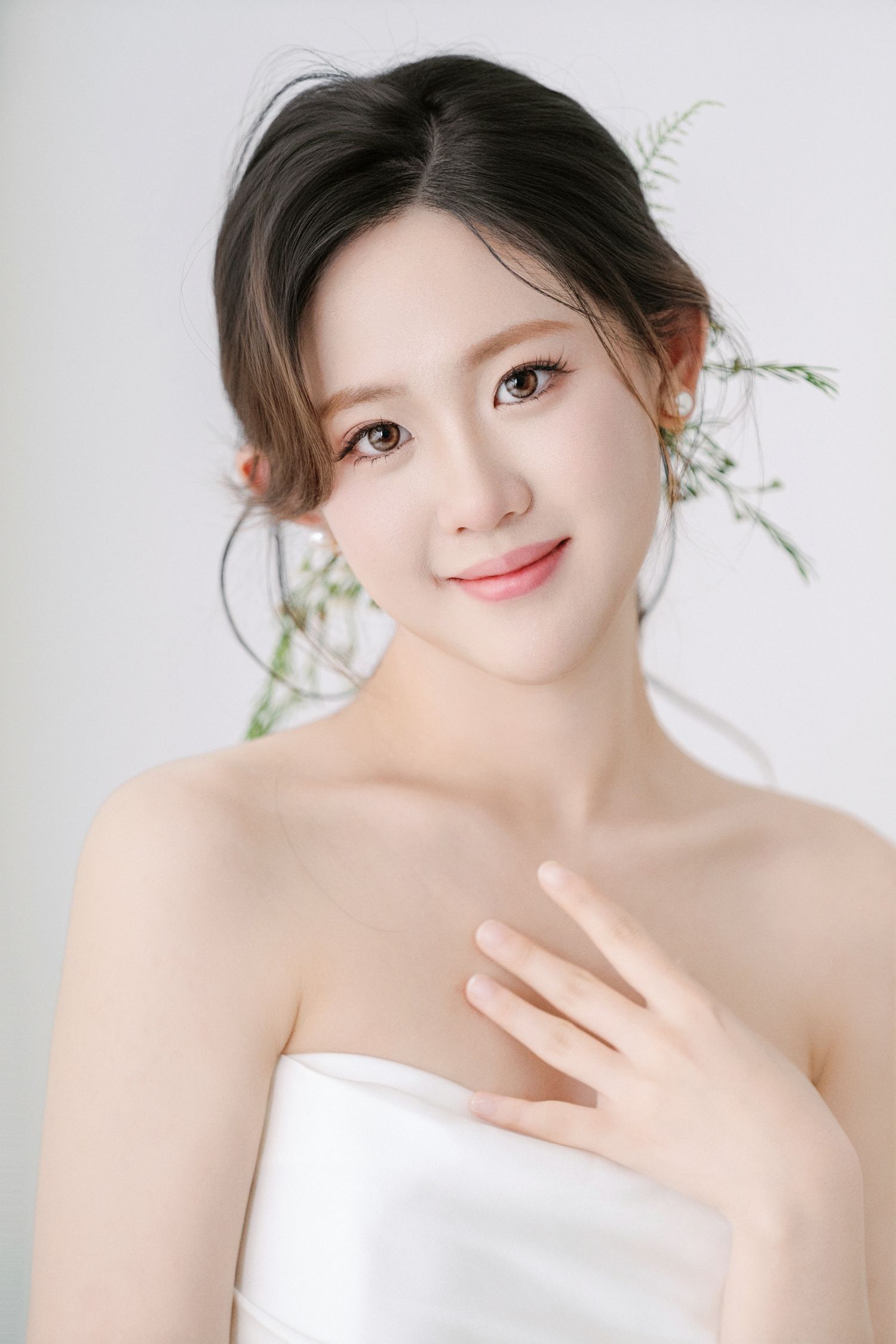 Soft and romantic studio portrait in white against a light background with natural floral accents.