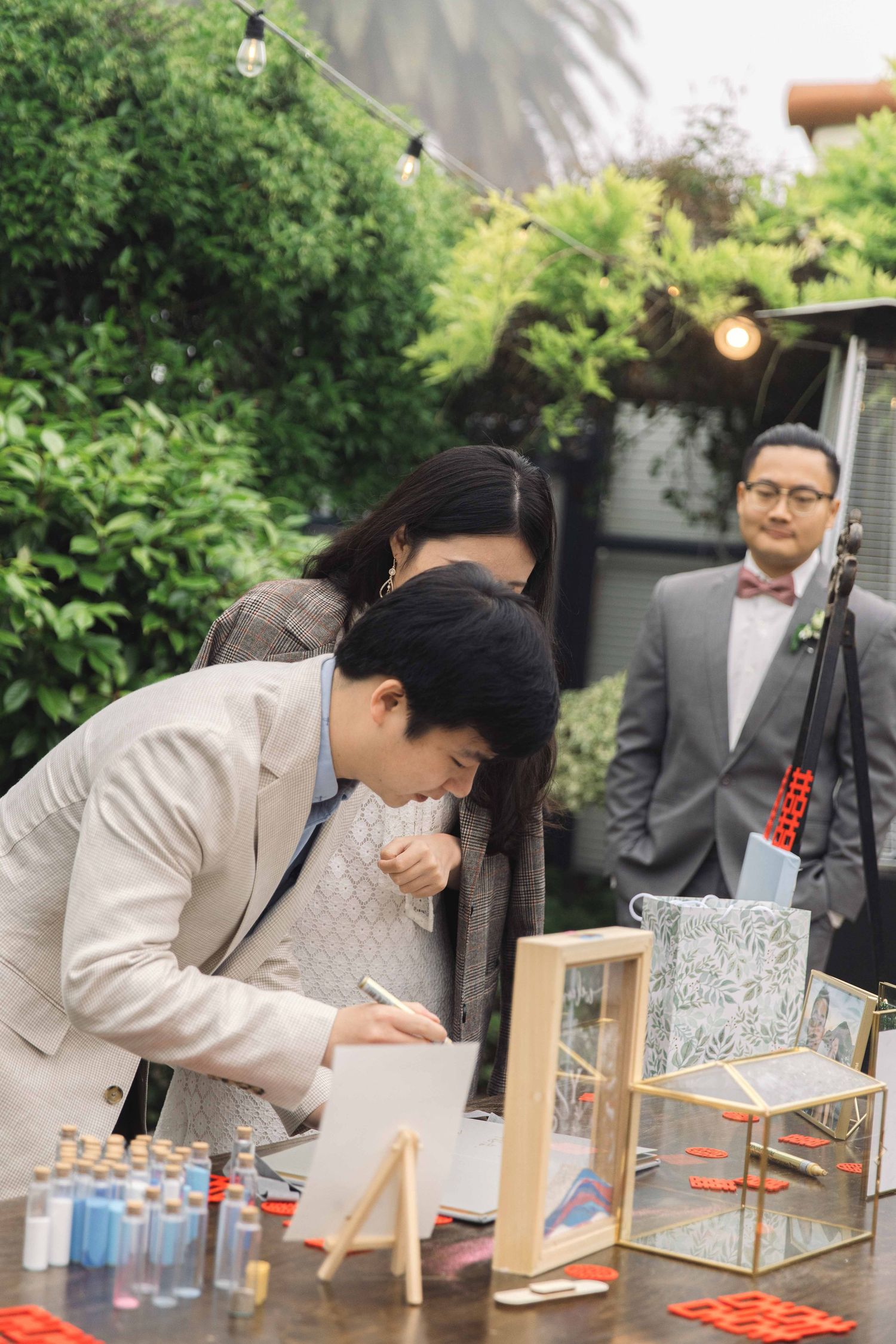 Guests participating in an interactive art activity at an outdoor wedding reception.
