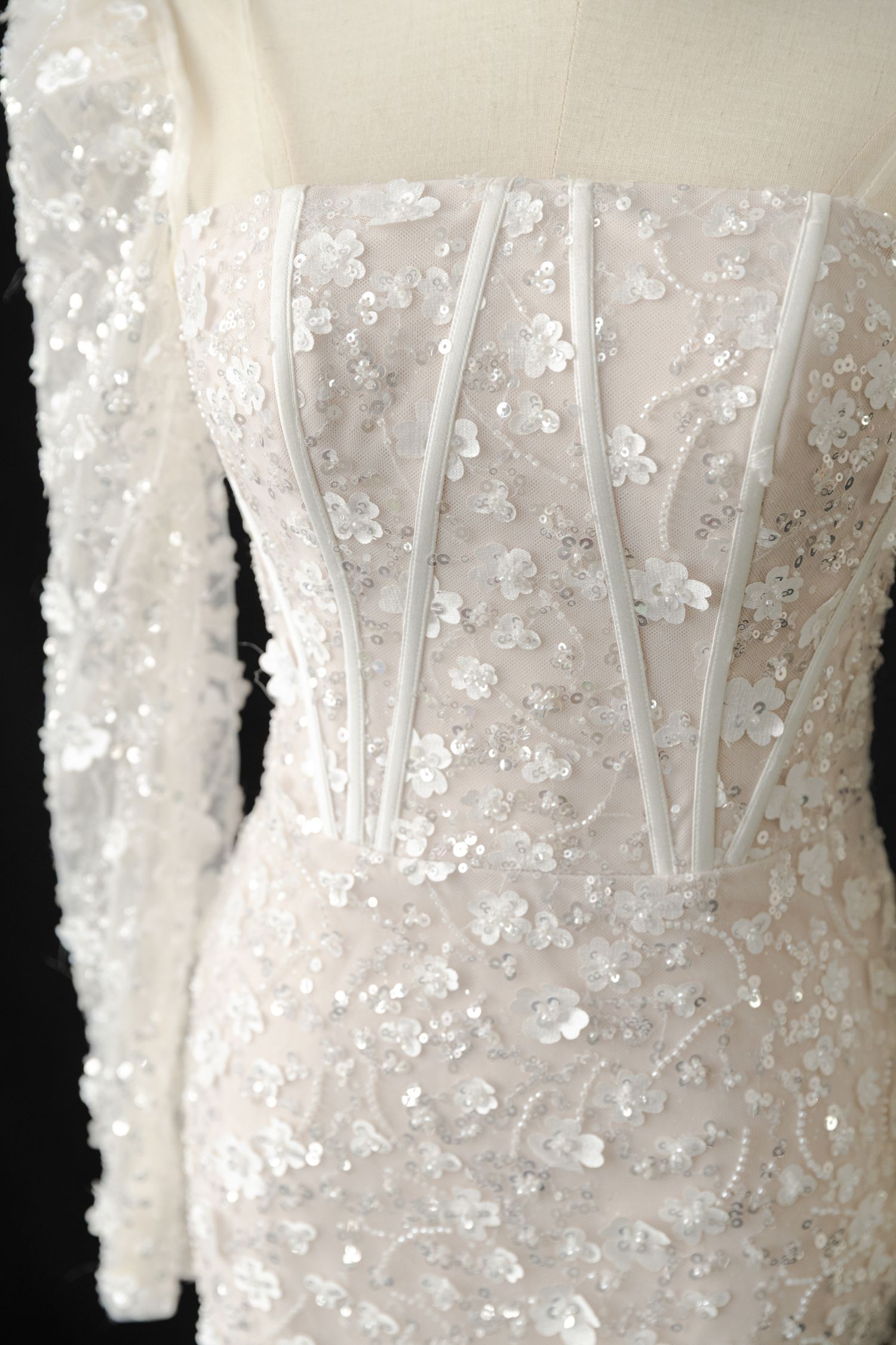 Close-up of intricate beaded pattern on white wedding dress bodice.