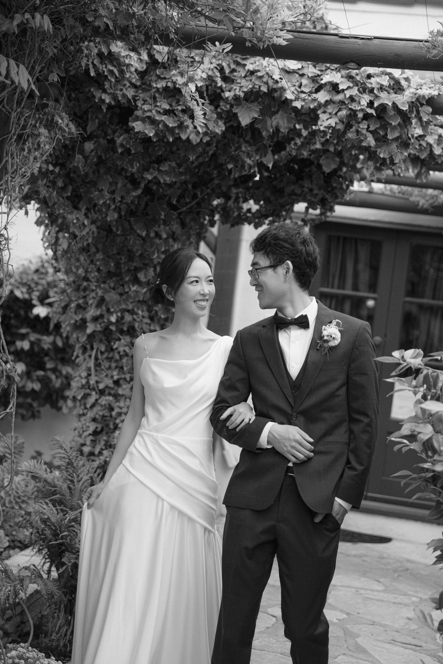 Wedding couple sharing intimate moments among garden greenery.