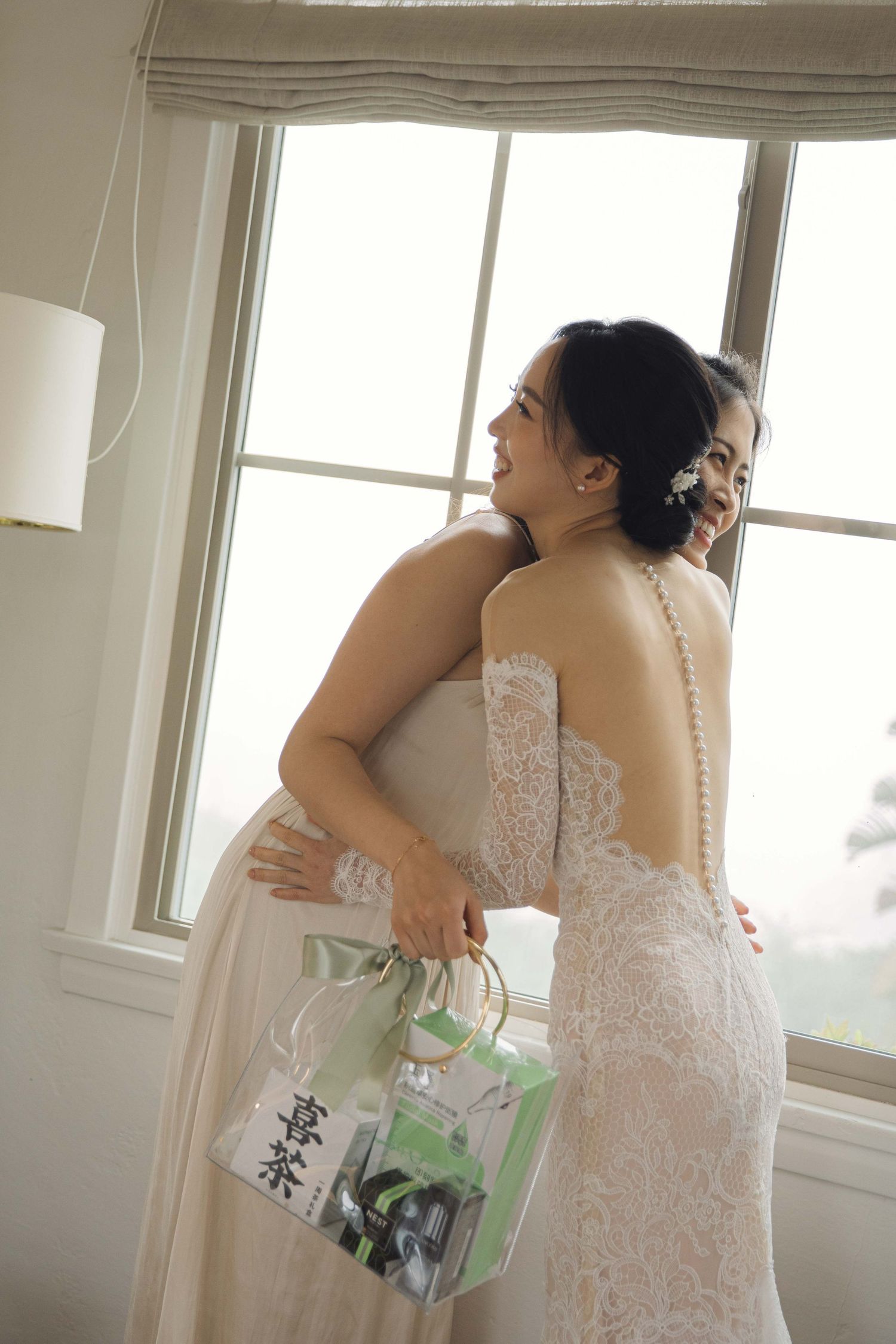 Close up of delicate lace wedding dress details in sunlit room.