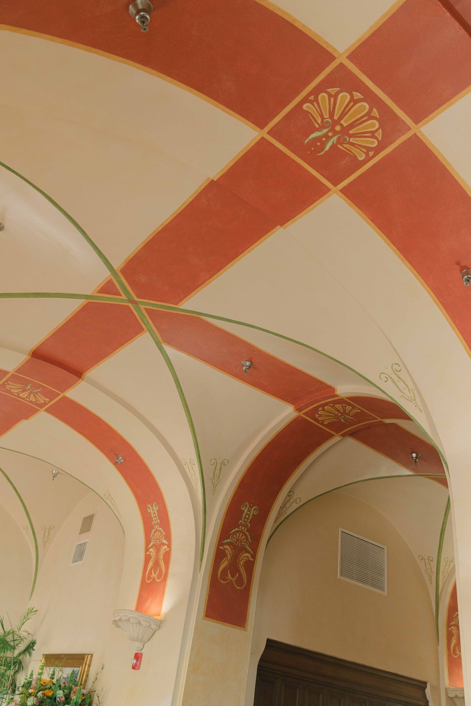 Ornate ceiling with terracotta and cream colored geometric patterns and decorative moldings.