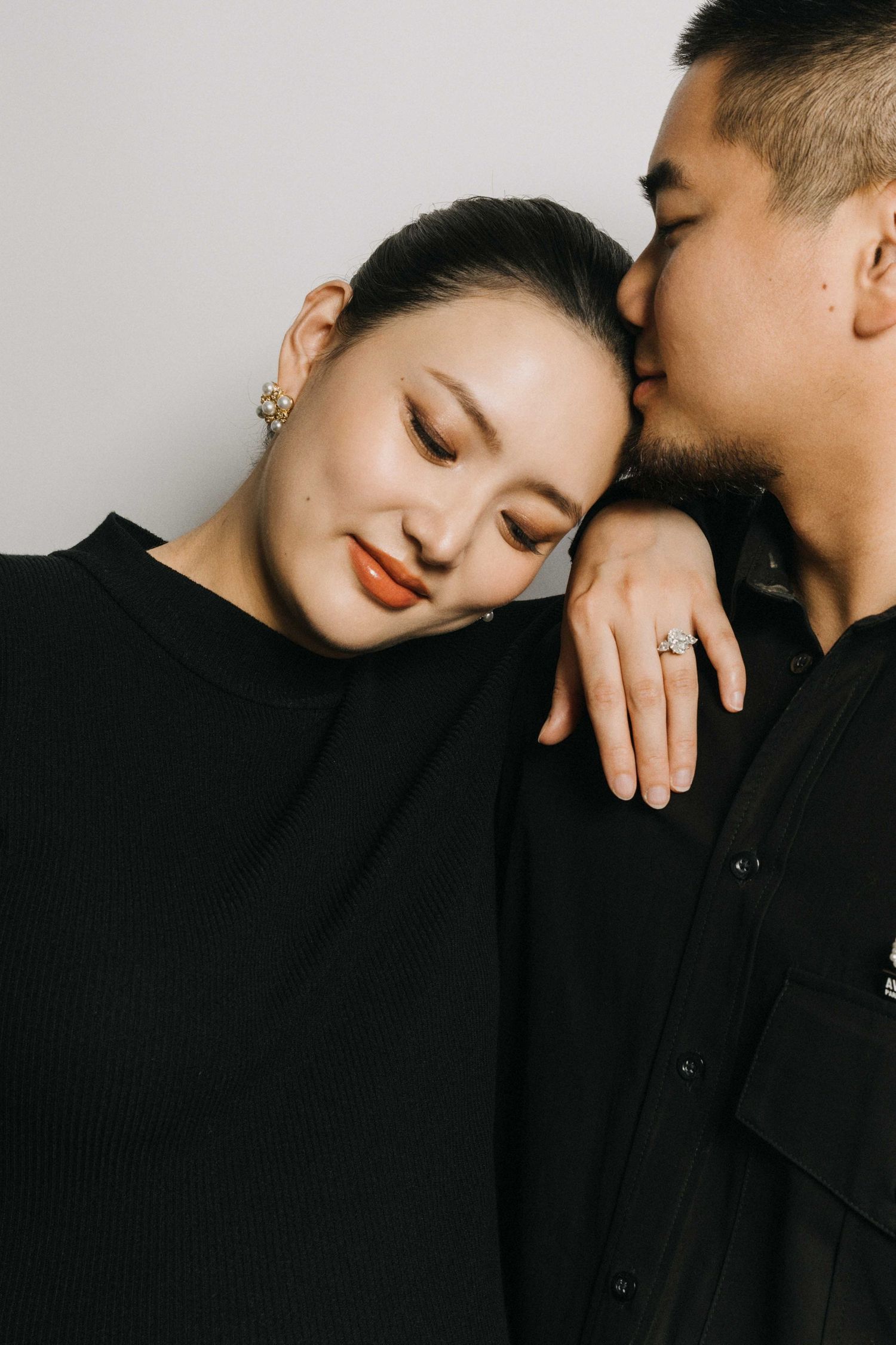 Romantic close-up portrait of couple sharing intimate moment in black attire.