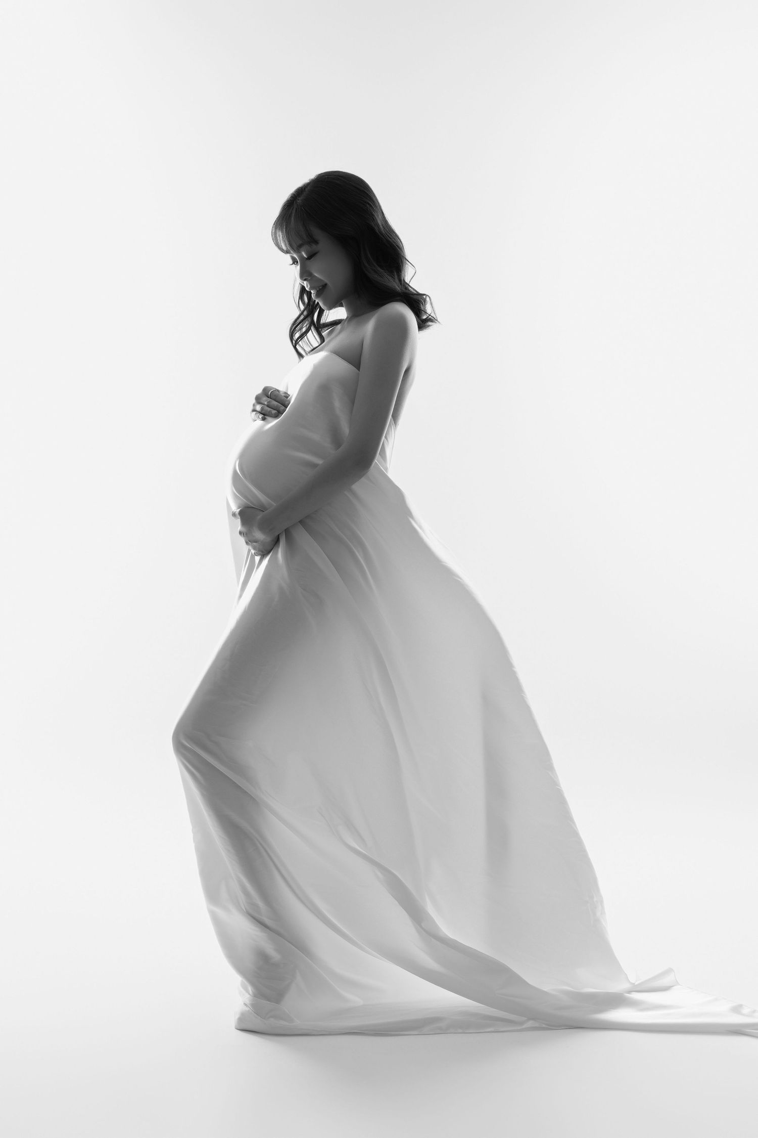 Minimalist maternity portraits in white against bright studio backdrop.