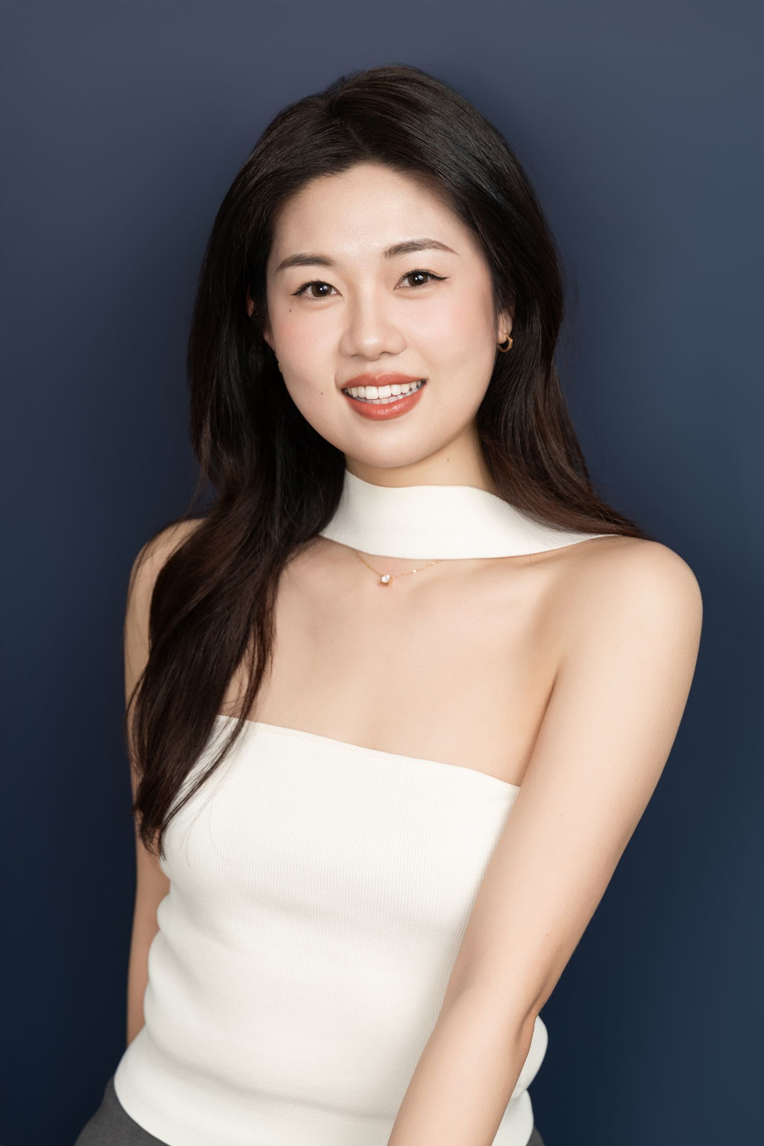 Studio portraits in white strapless dress against dark blue background.