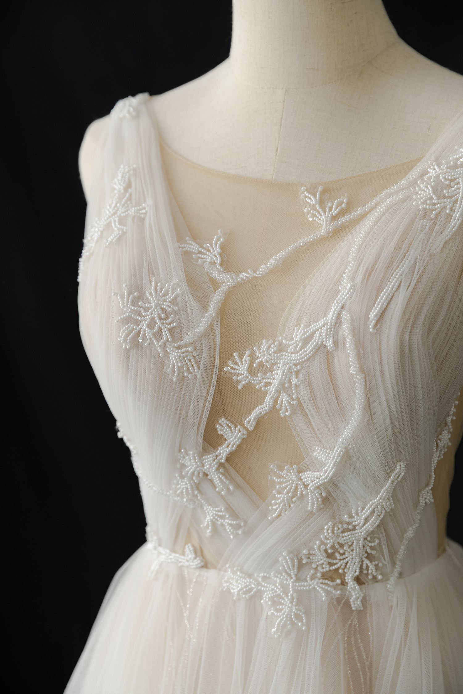 Detailed view of sheer embroidered bodice on white wedding gown.