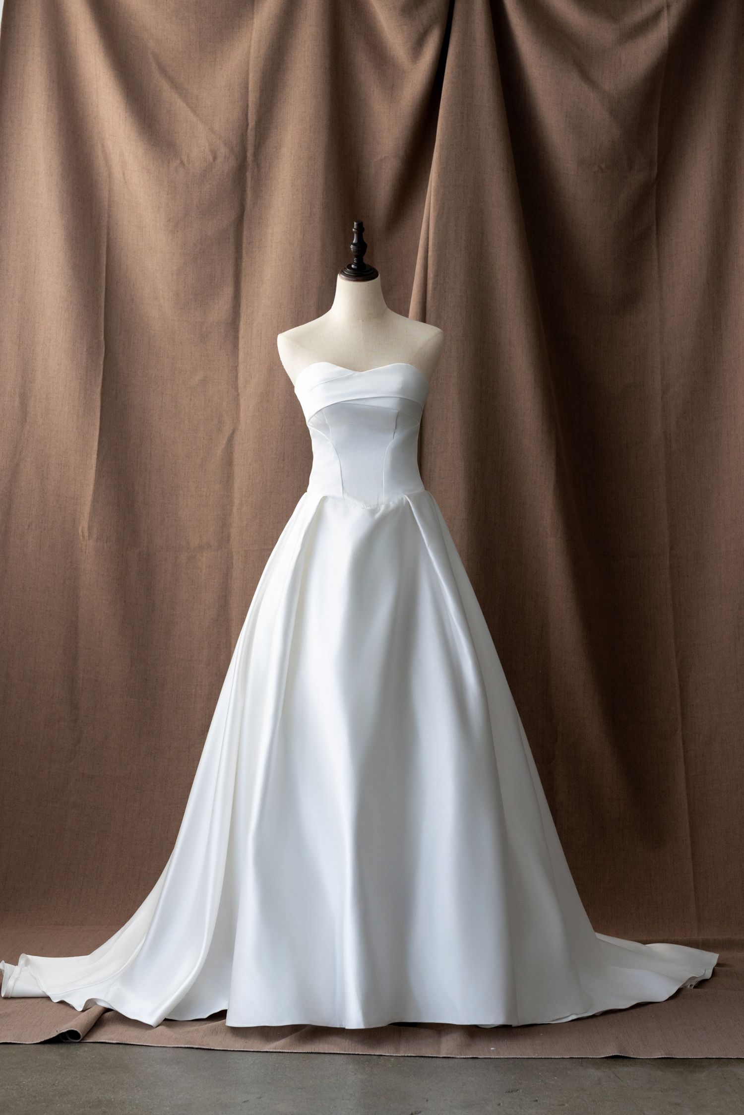 Minimalist white wedding dress with clean lines and full pleated skirt shown from side angle.