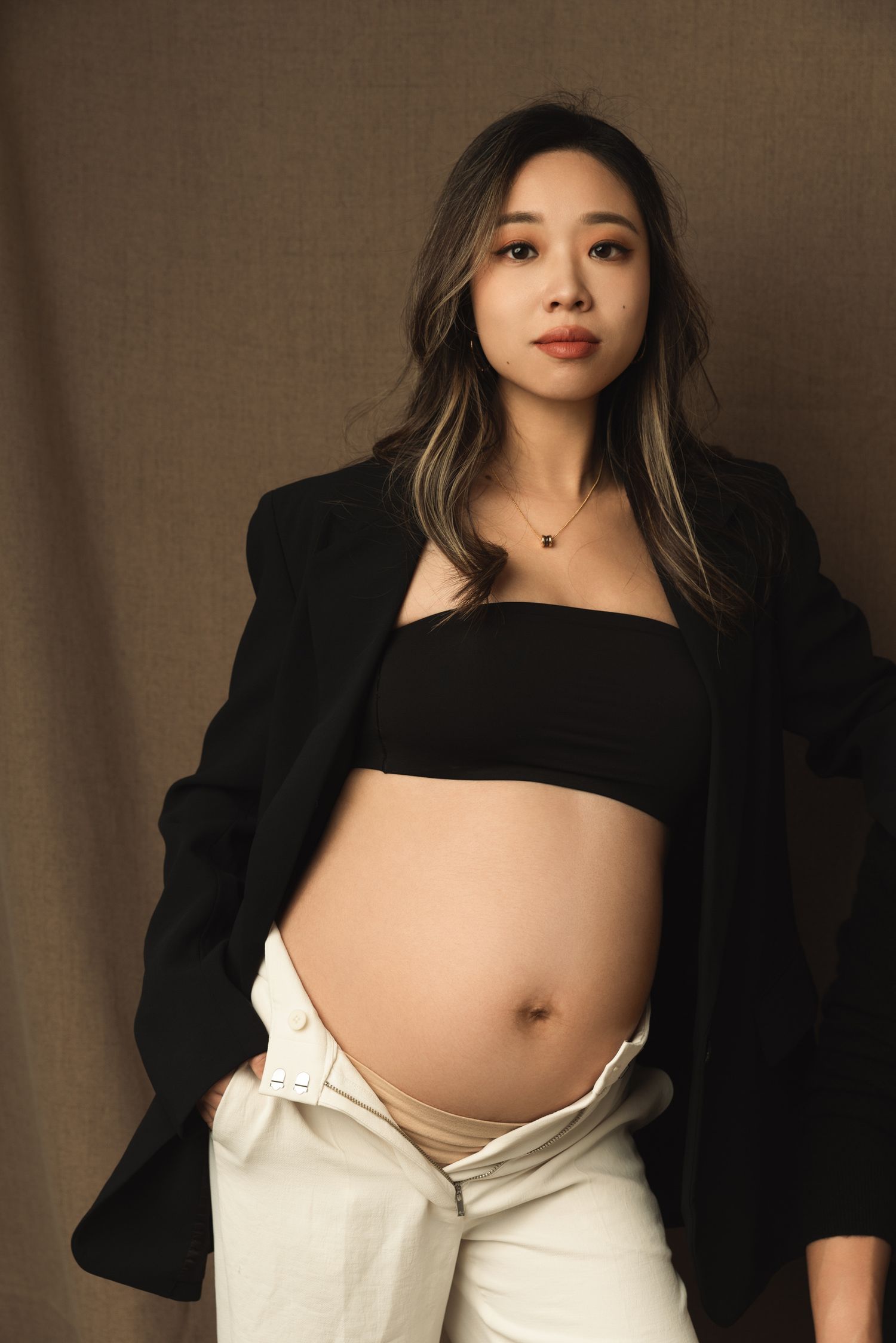 Maternity photos showing pregnant belly with black top and white pants.