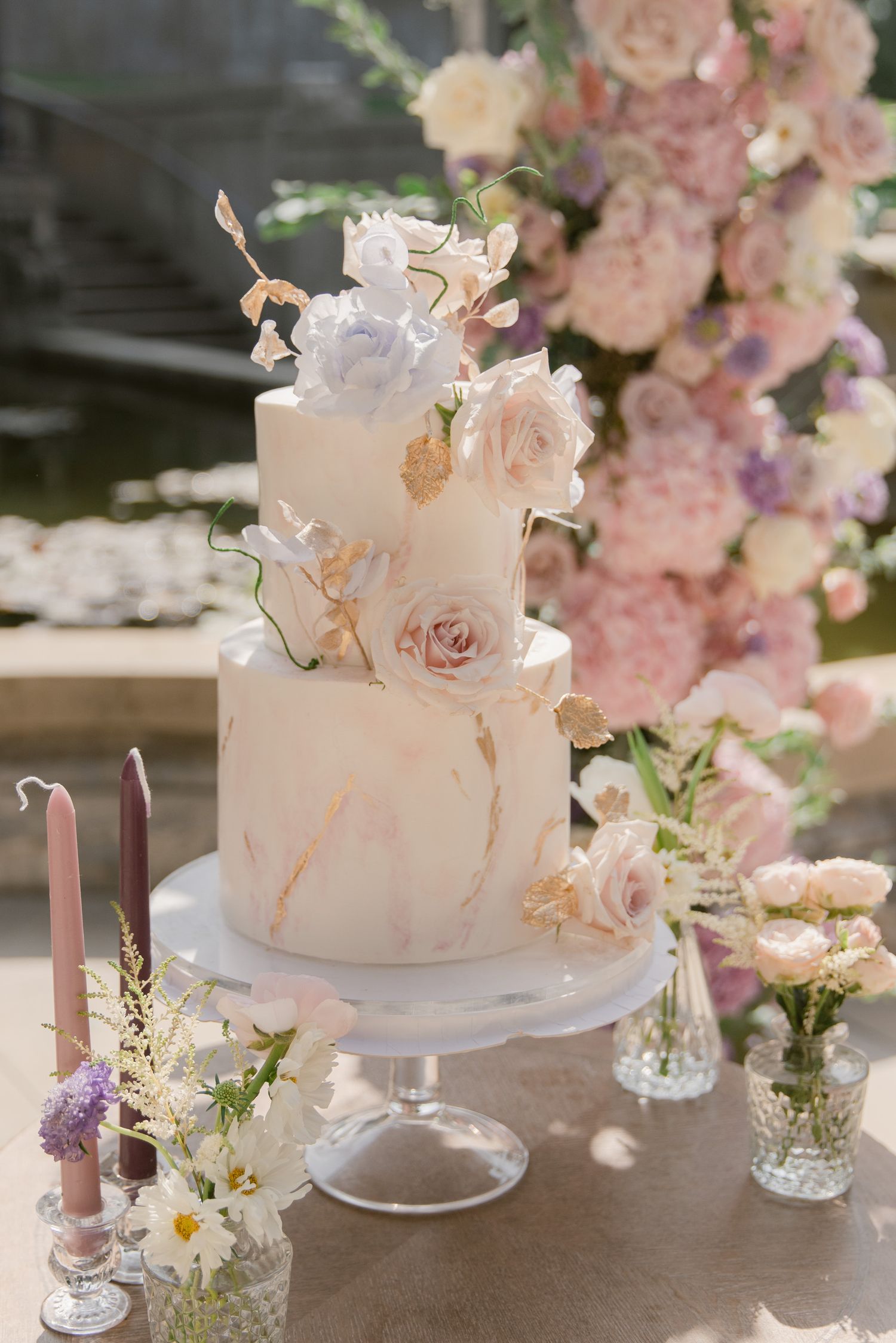White tiered wedding cake adorned with soft pink roses and delicate floral arrangements on display.