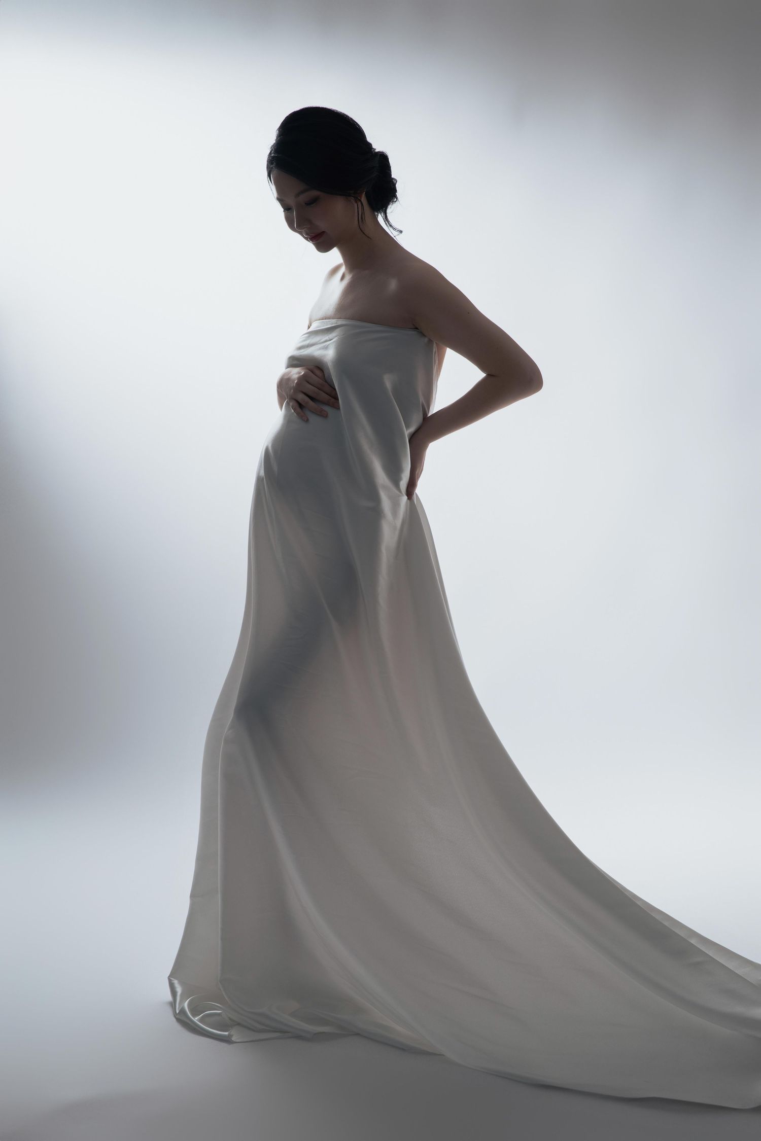 Ethereal maternity portraits with flowing white fabric against light background.