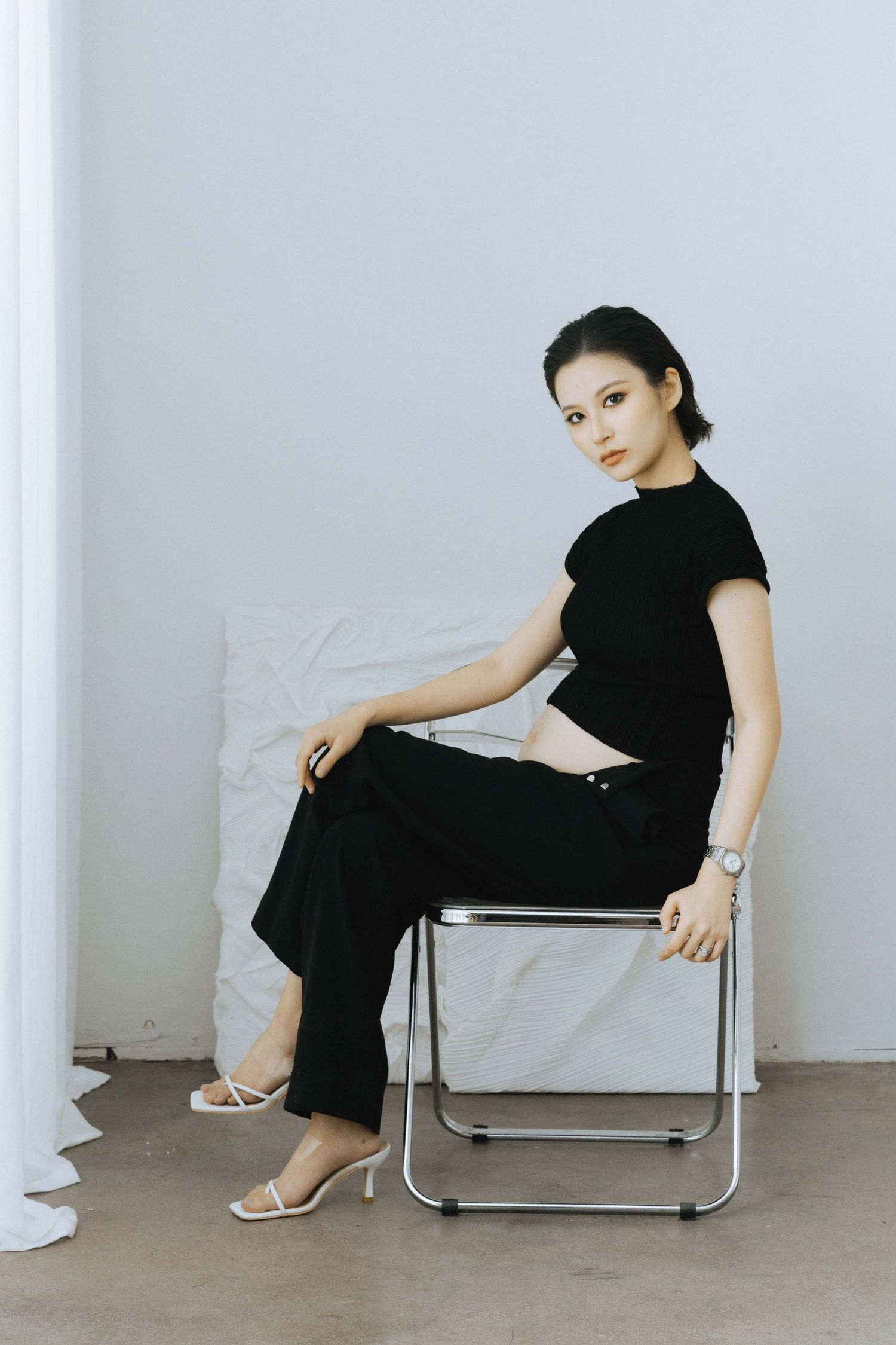 Series of poses showing someone in black attire reclining on a modern metal chair.