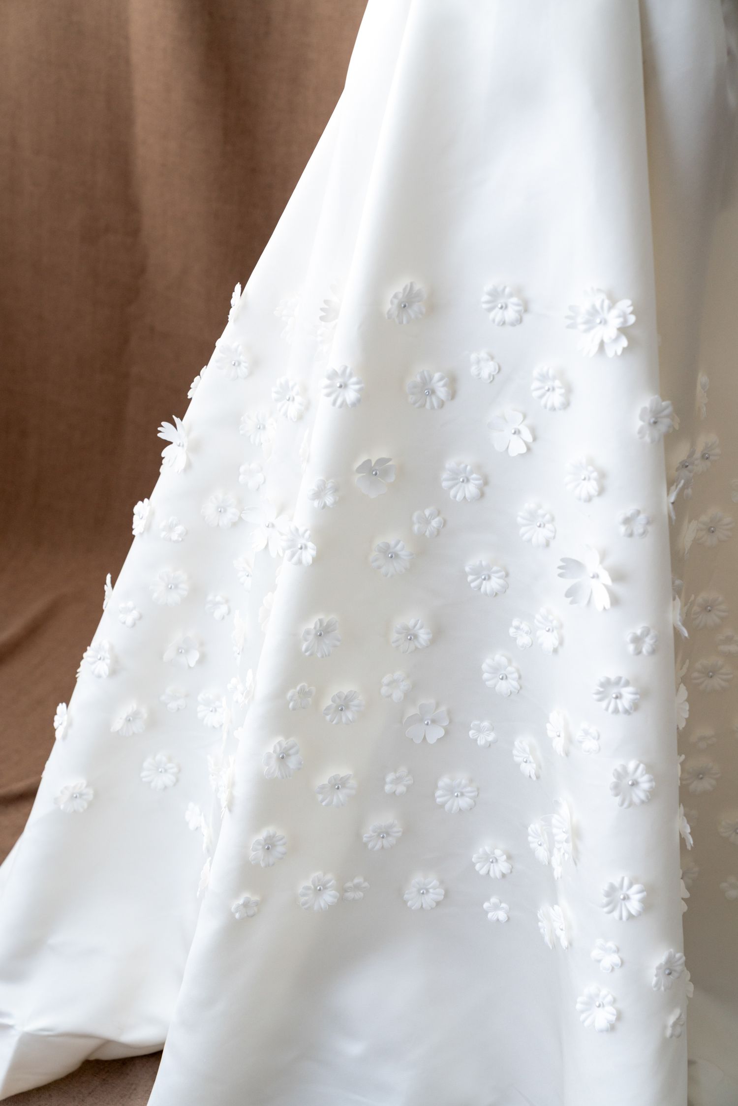 Detailed view of delicate white floral embellishments on wedding dress fabric.