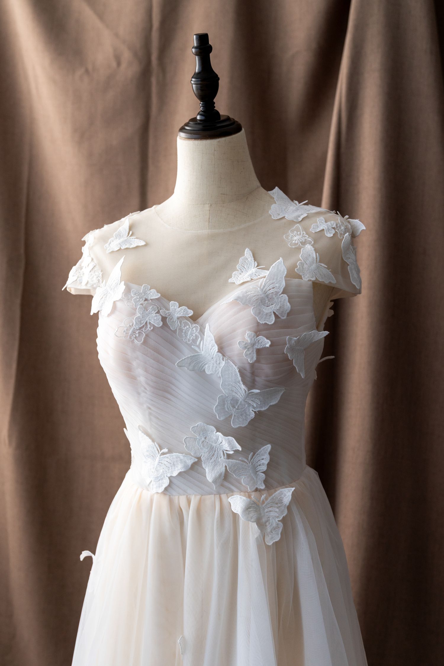 Empire waist wedding gown with floral appliques and ruched bodice displayed on mannequin.