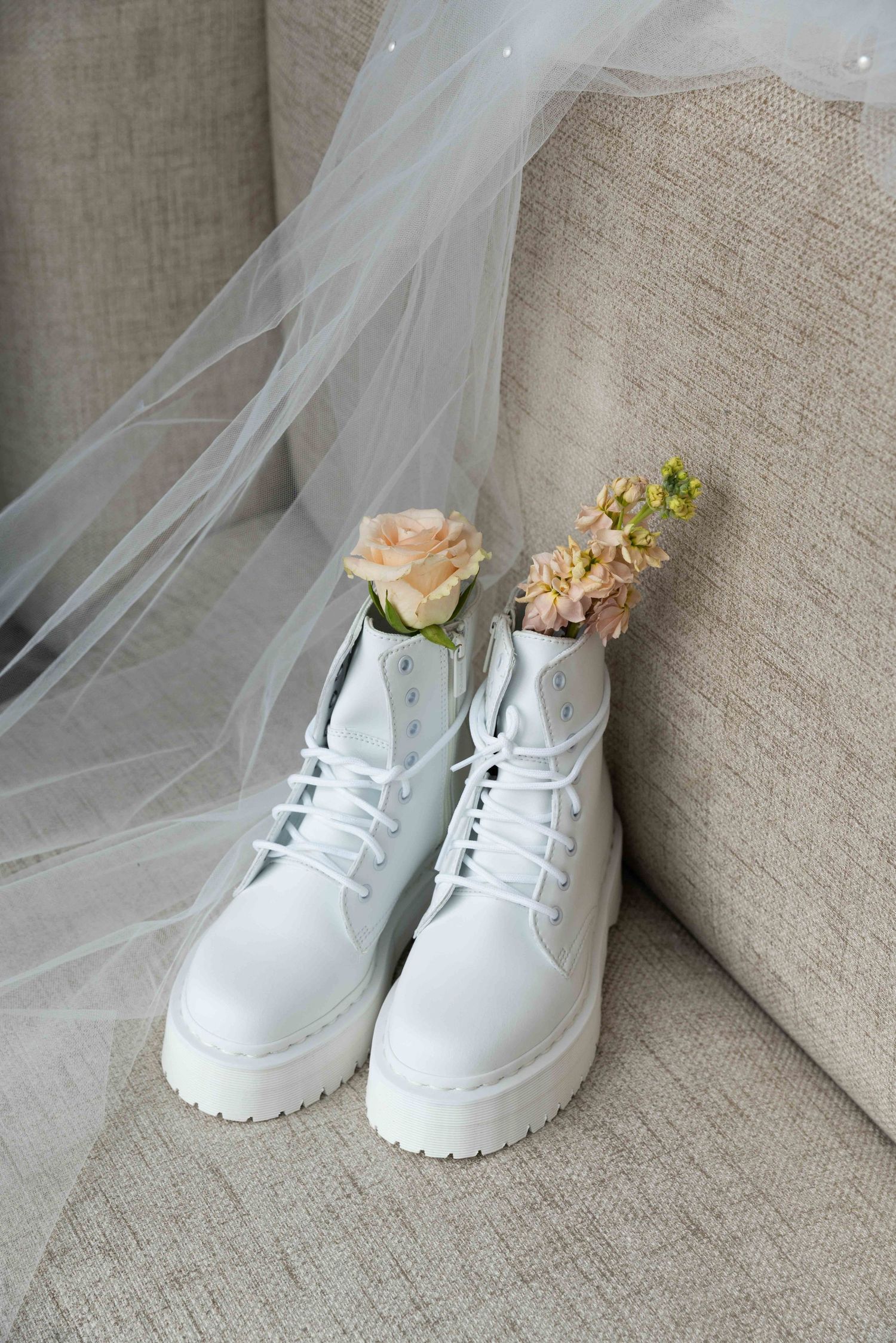 White platform sneakers decorated with delicate peach and cream flowers and sheer tulle veil for a wedding.